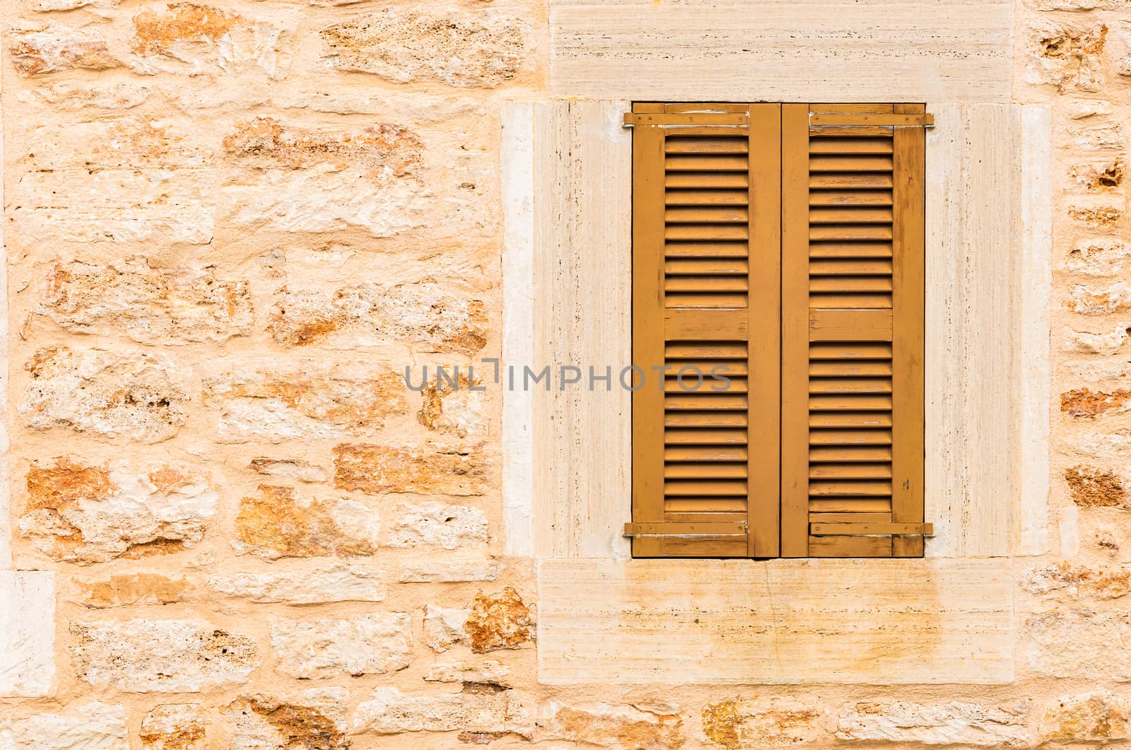Detail view of brown wooden window shutters and stone wall