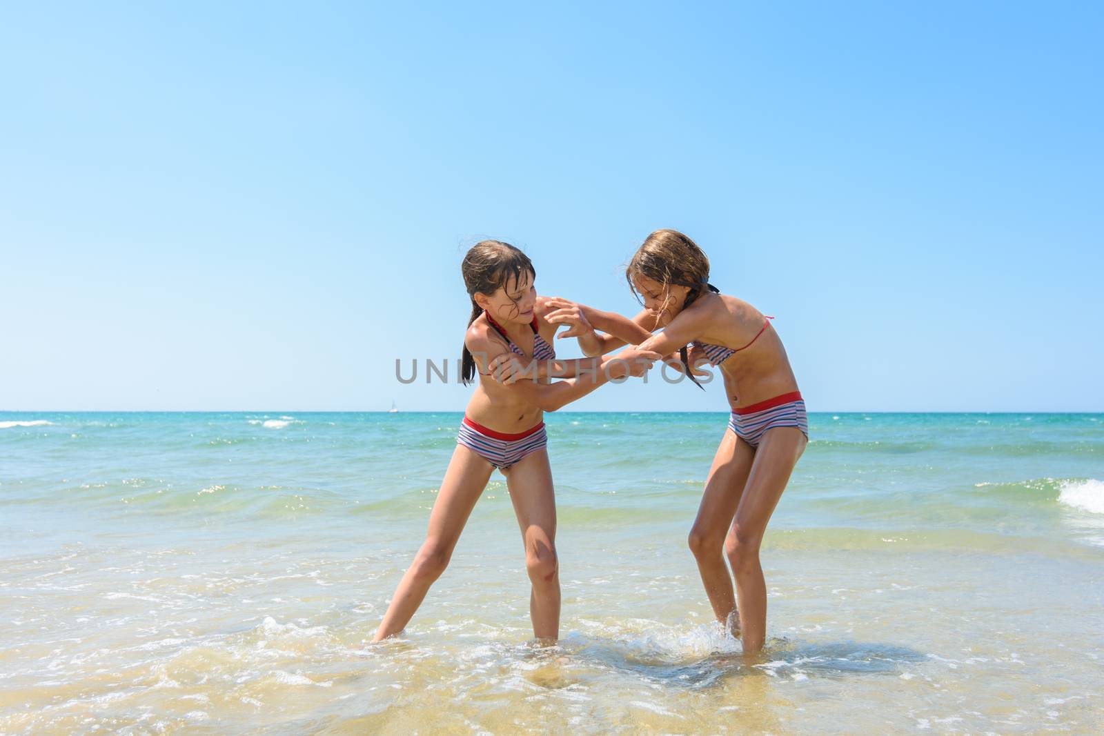 Two girls fight on the sandy beach of the sea