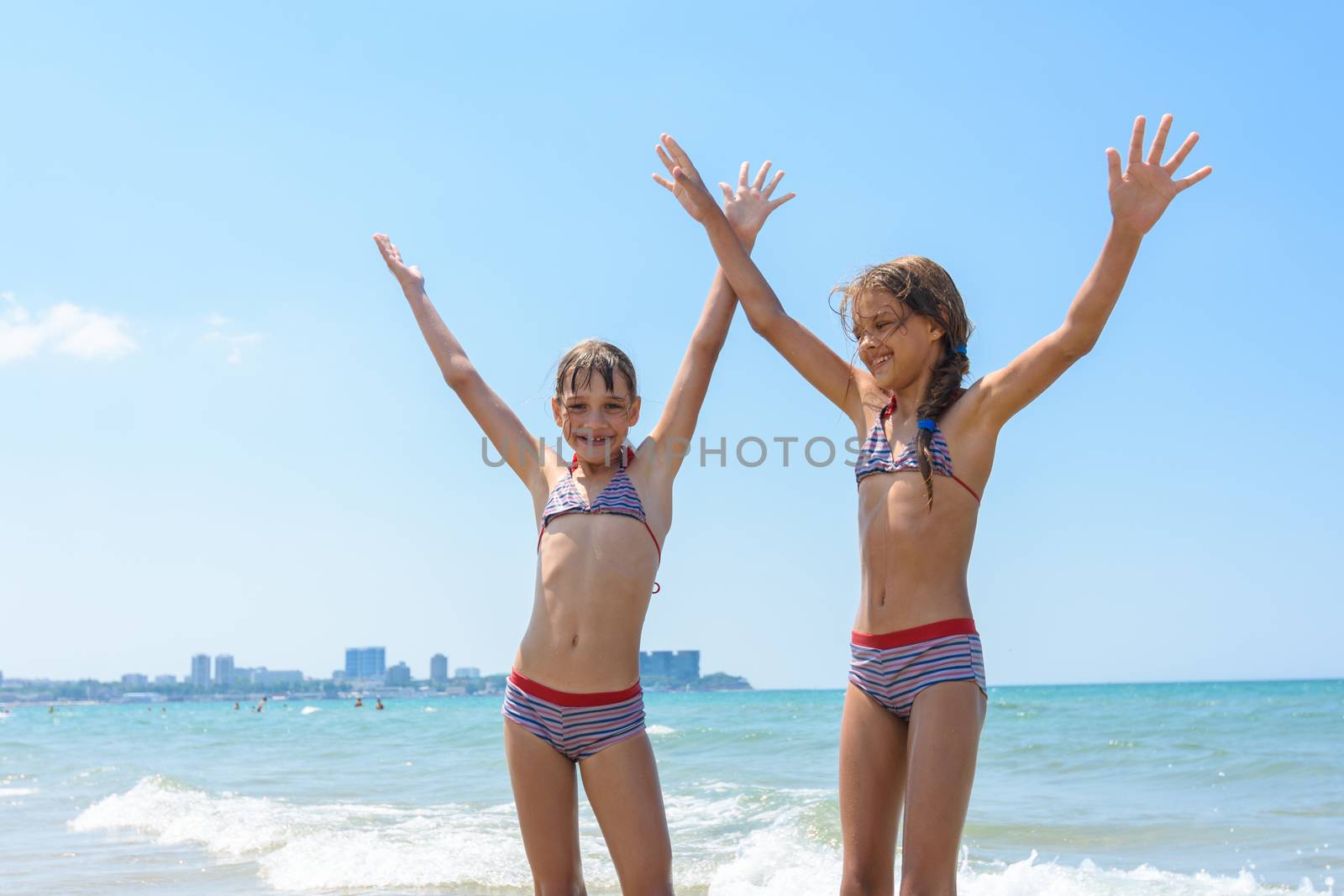 Two girls joyfully raised their hands up on the sea on vacation and swimming