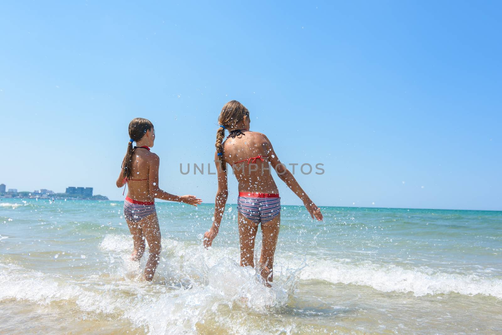 Two girls went knee-deep into the water and enjoy the sea