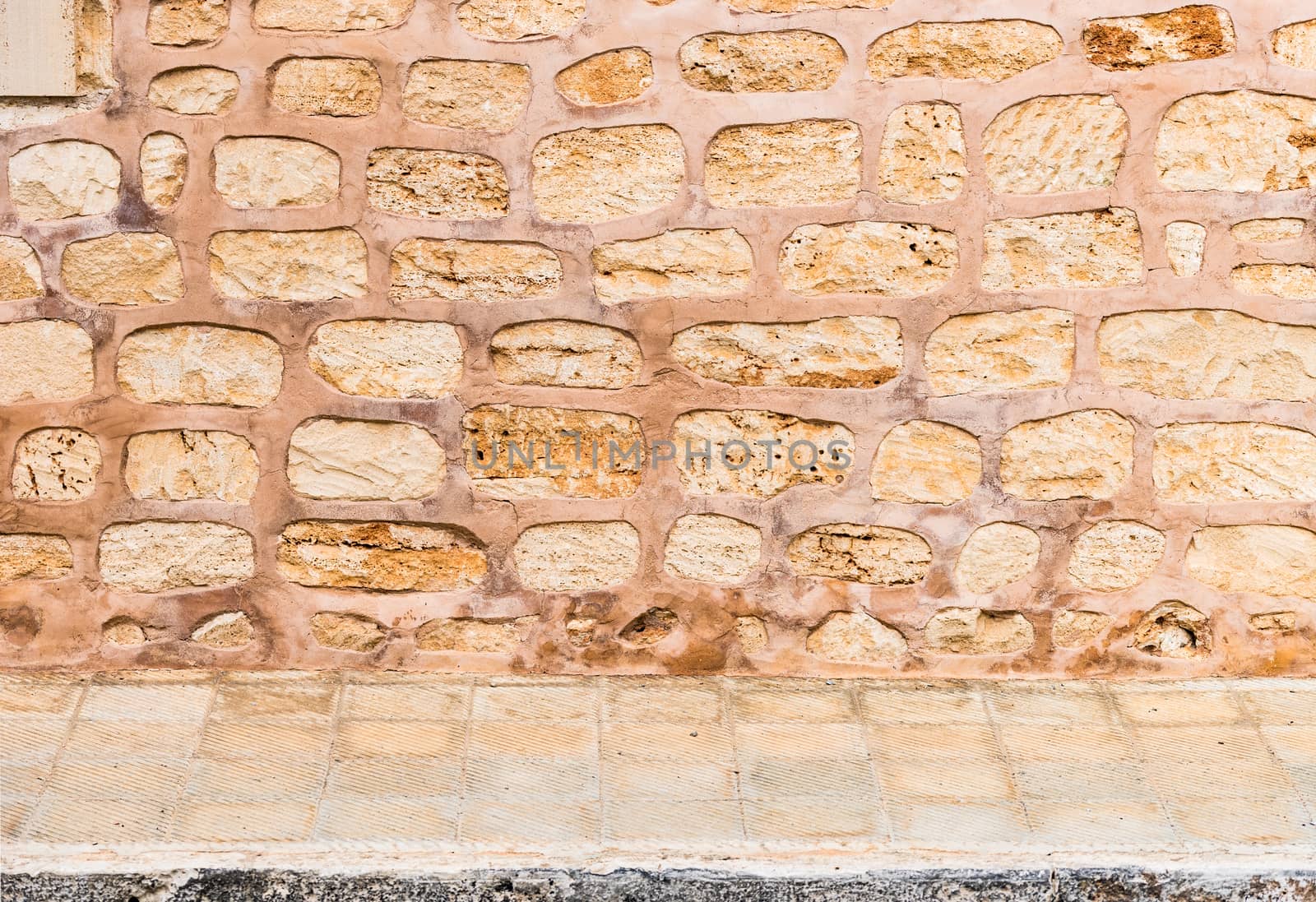 Rustic old stone wall texture background with pavement