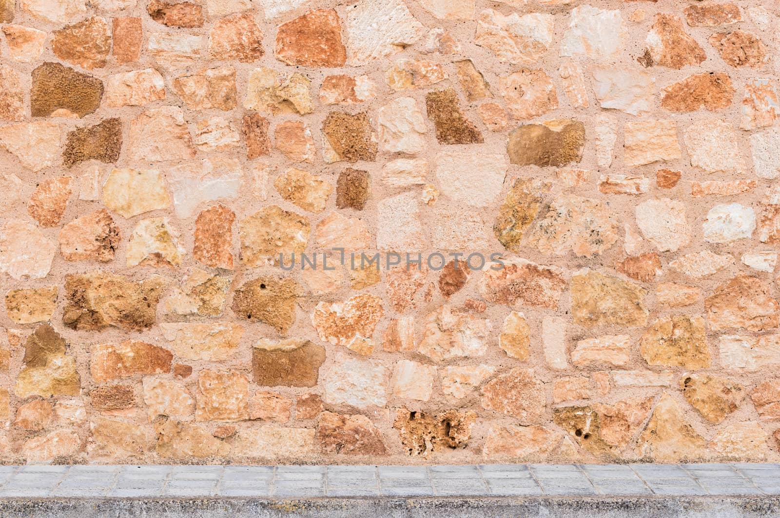 Rustic stone wall background texture with sidewalk