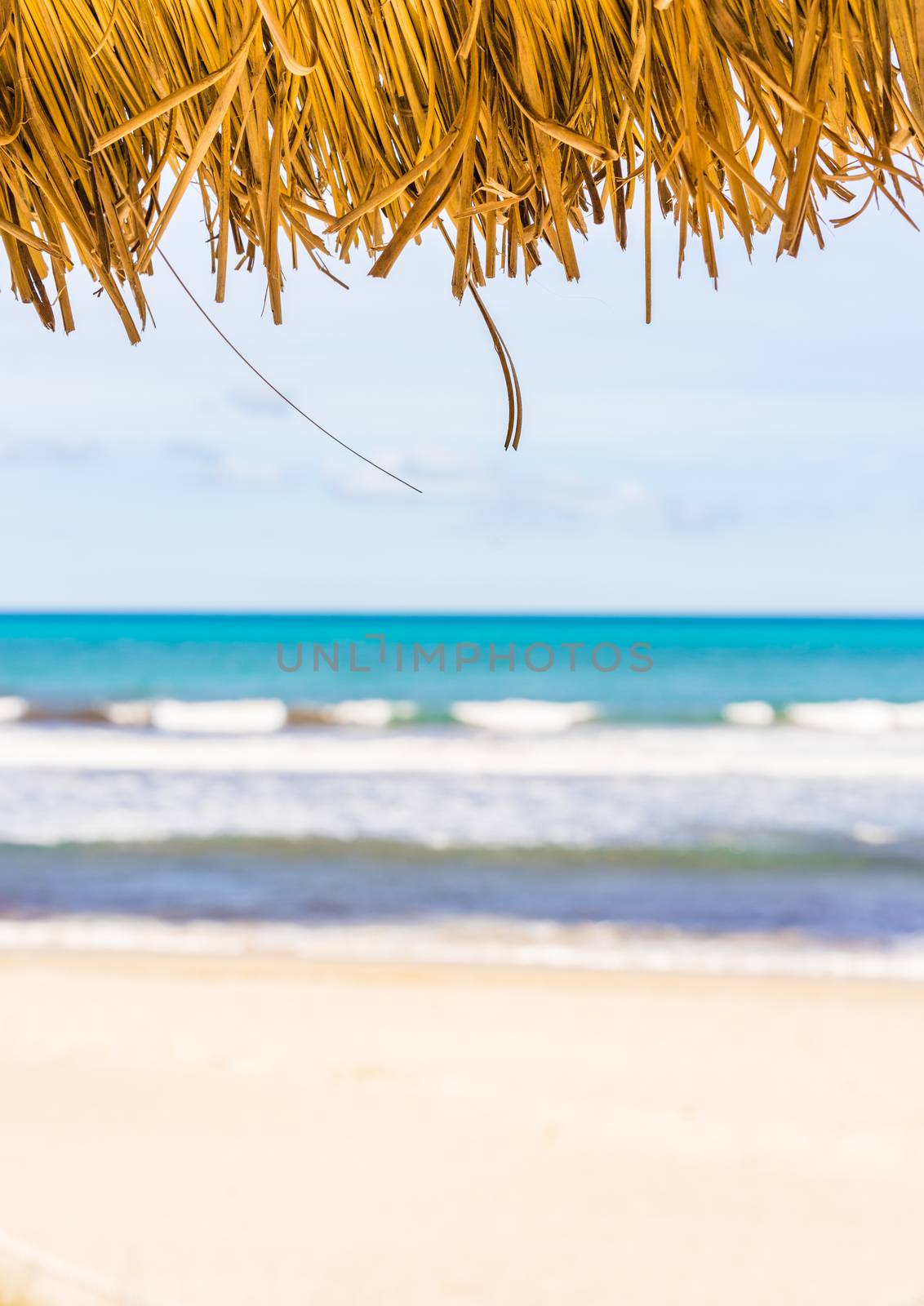 Sandy beach summer holiday background concept with straw sunshade umbrella