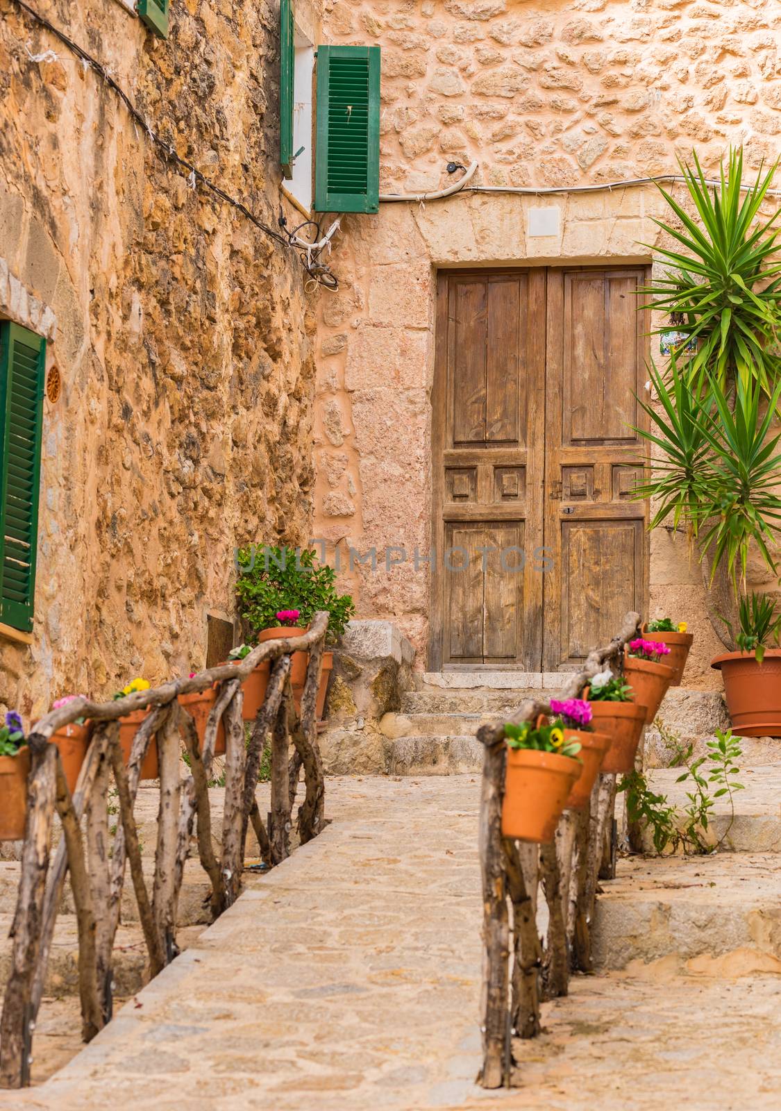 Idyllic house entrance with beautiful flower pots decoration on wooden fence, in Valldemossa on Mallorca island