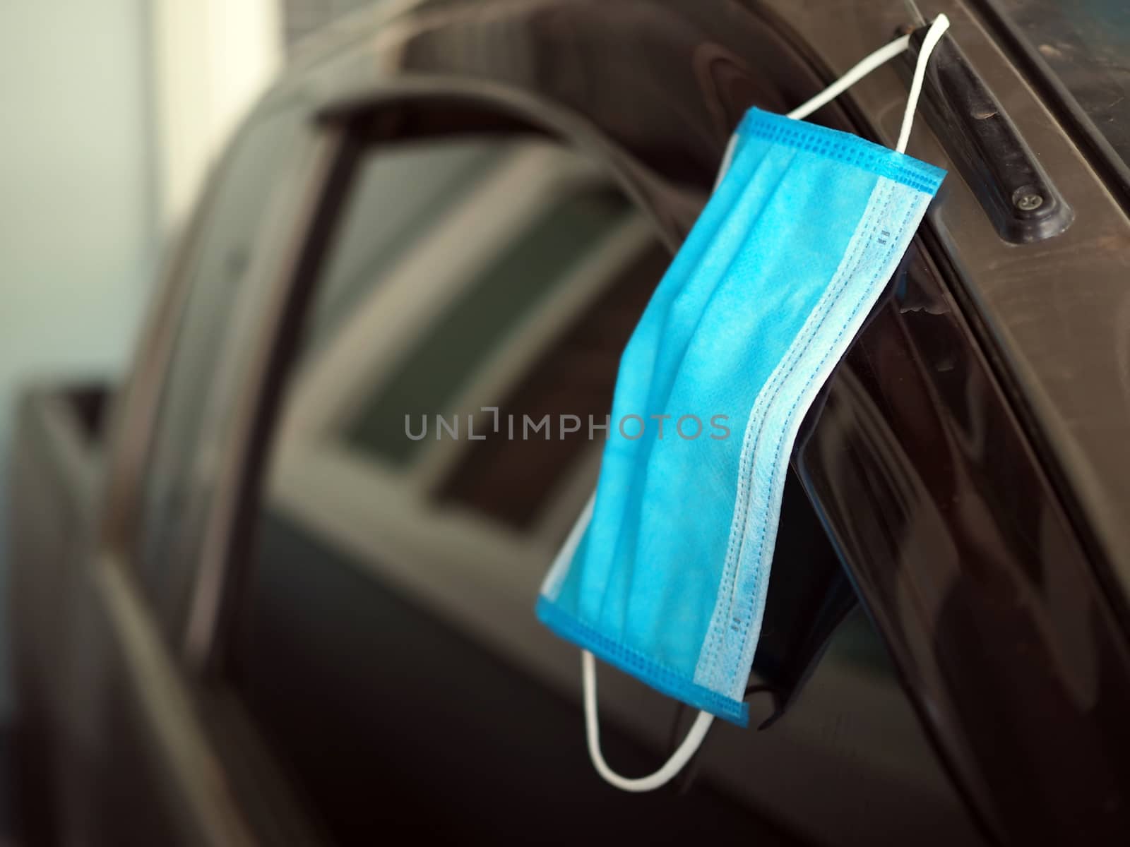 A face mask hanging from the side of the car door. To prepare at by Unimages2527