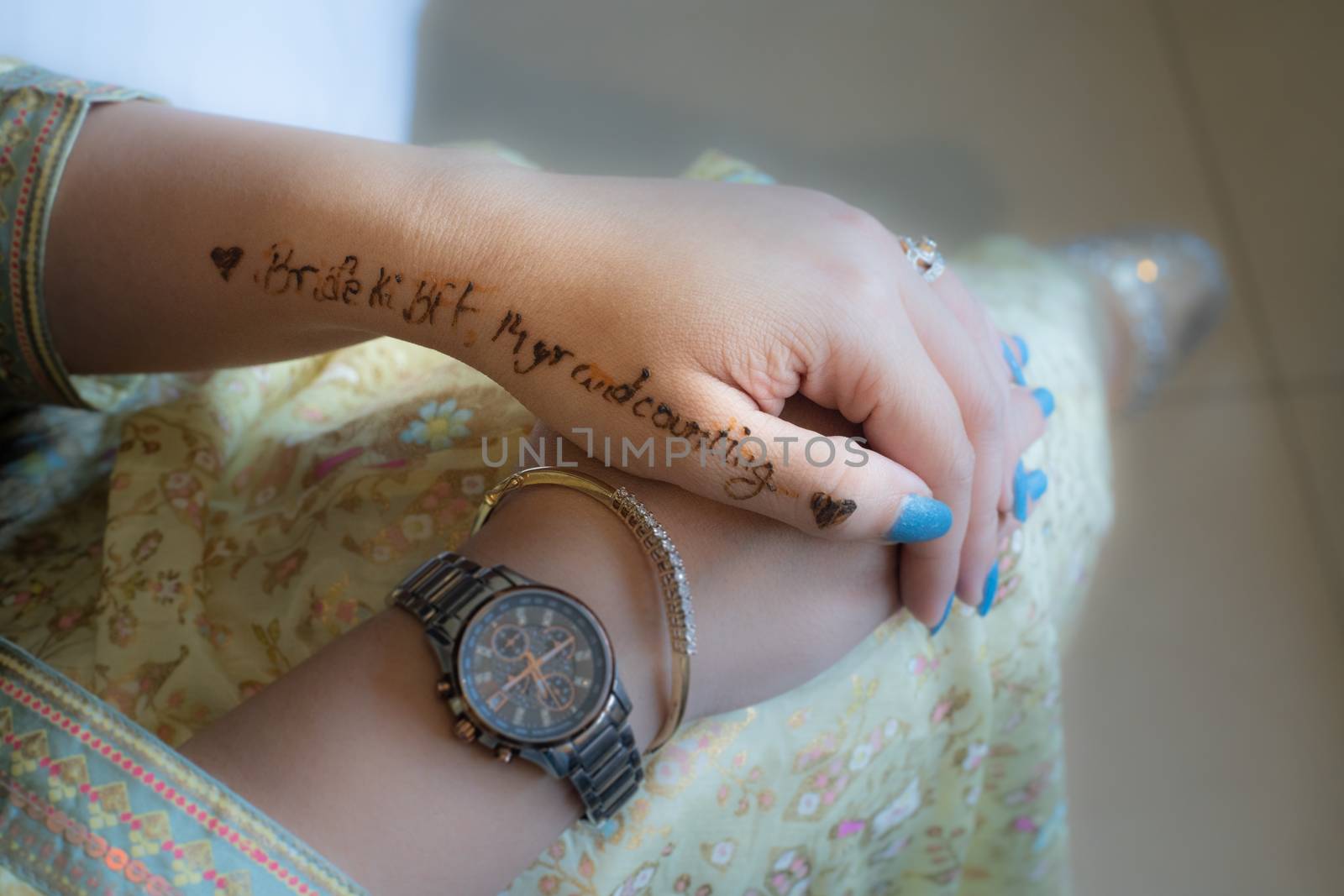 Young indian girl decked in white gold dress preparing for a wedding words bride to be BFF written in henna tattoo. Shows the preparation for a indian wedding by the bridesmaids