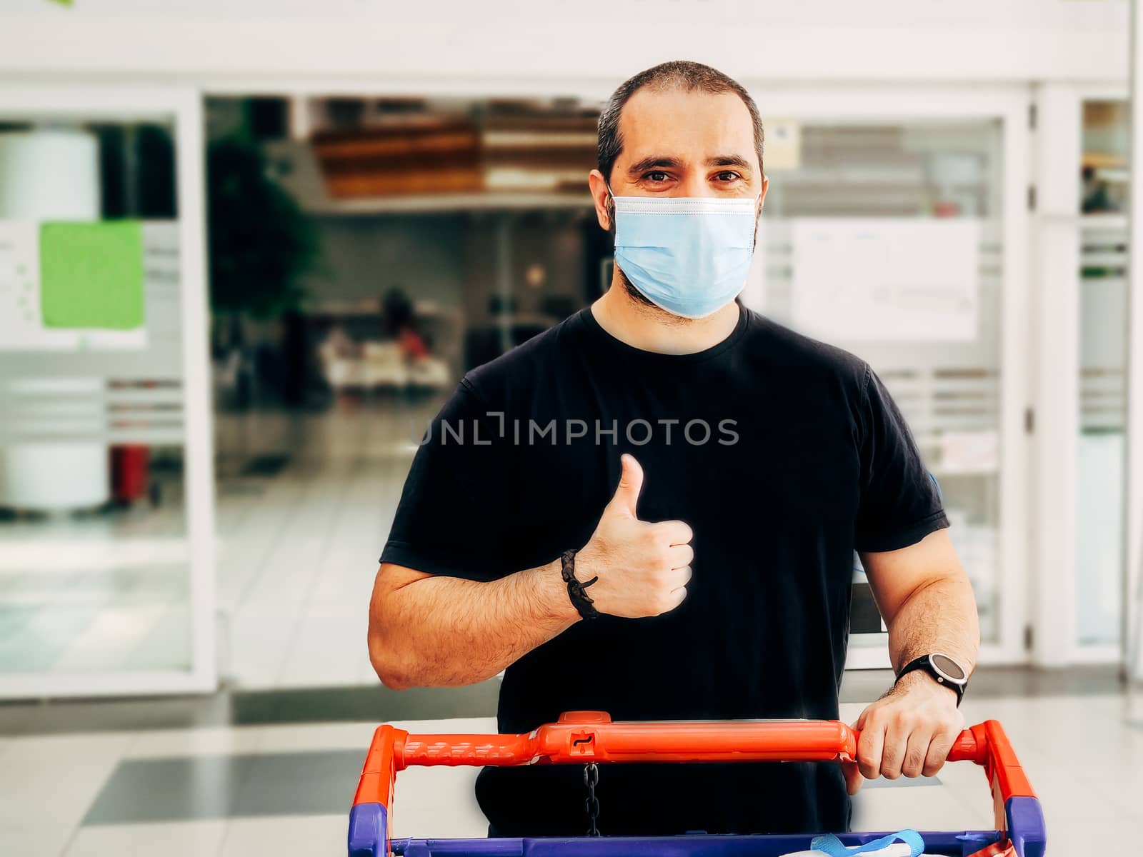 man in medical mask shopping at supermarket with thumb up.