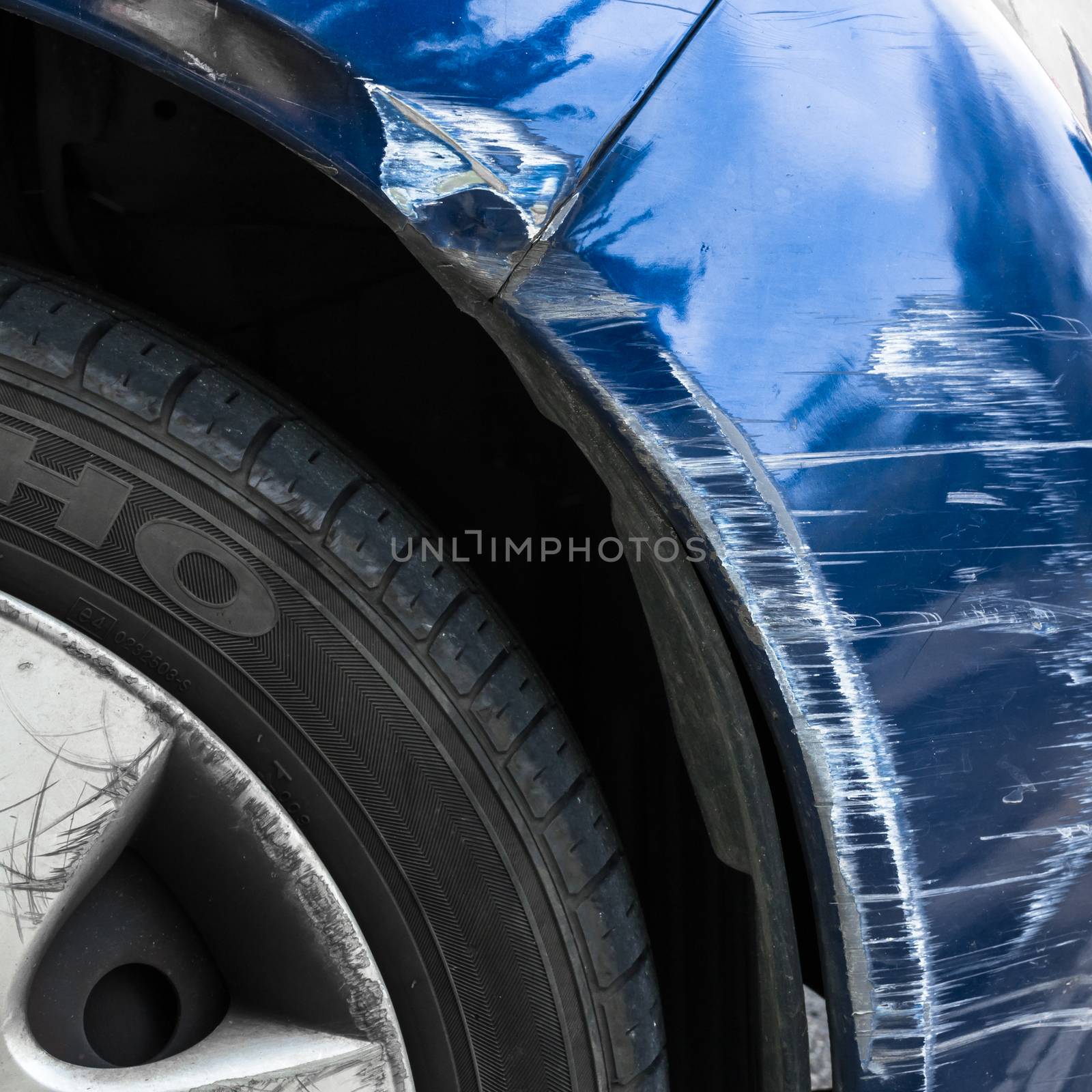 Accident damage to the front side of a blue car.