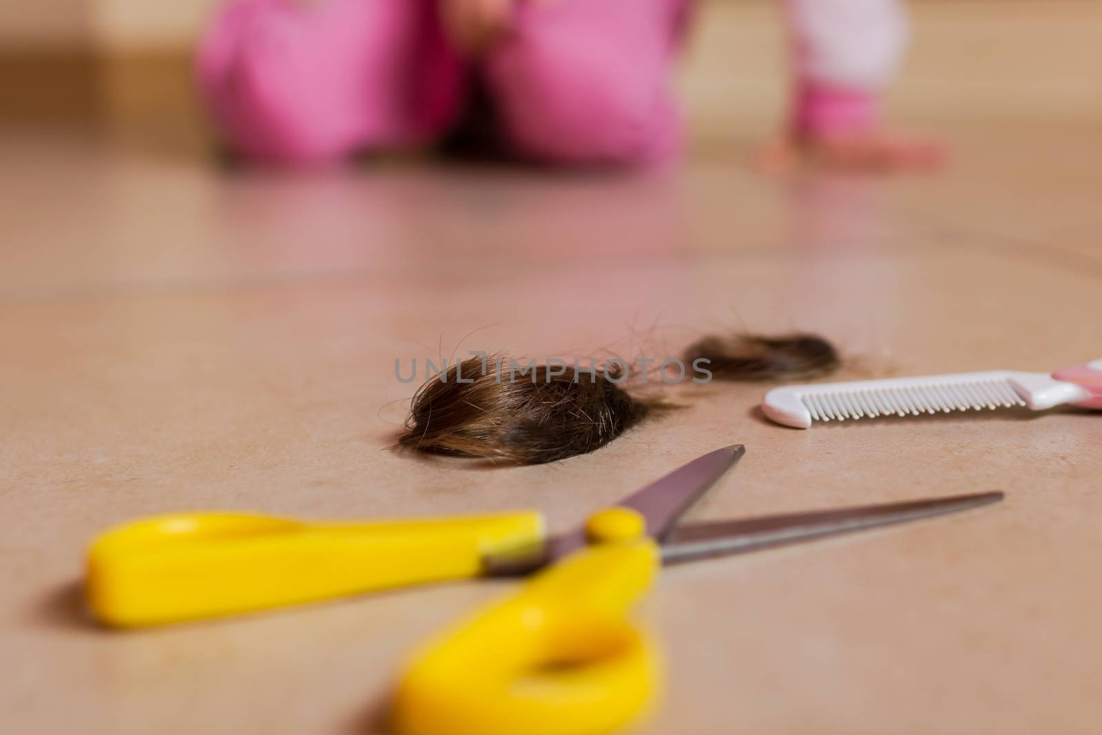 Selective focus on hair and cutting shears with baby blurry on background.