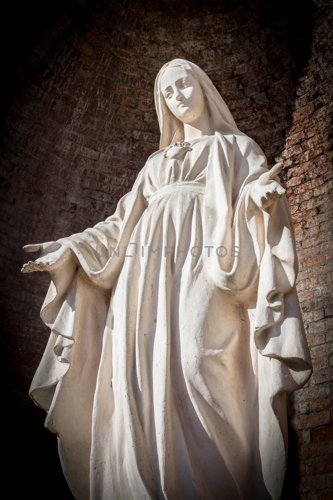 Statue of Virgin Mary in Roman Catholic Church on wall background.