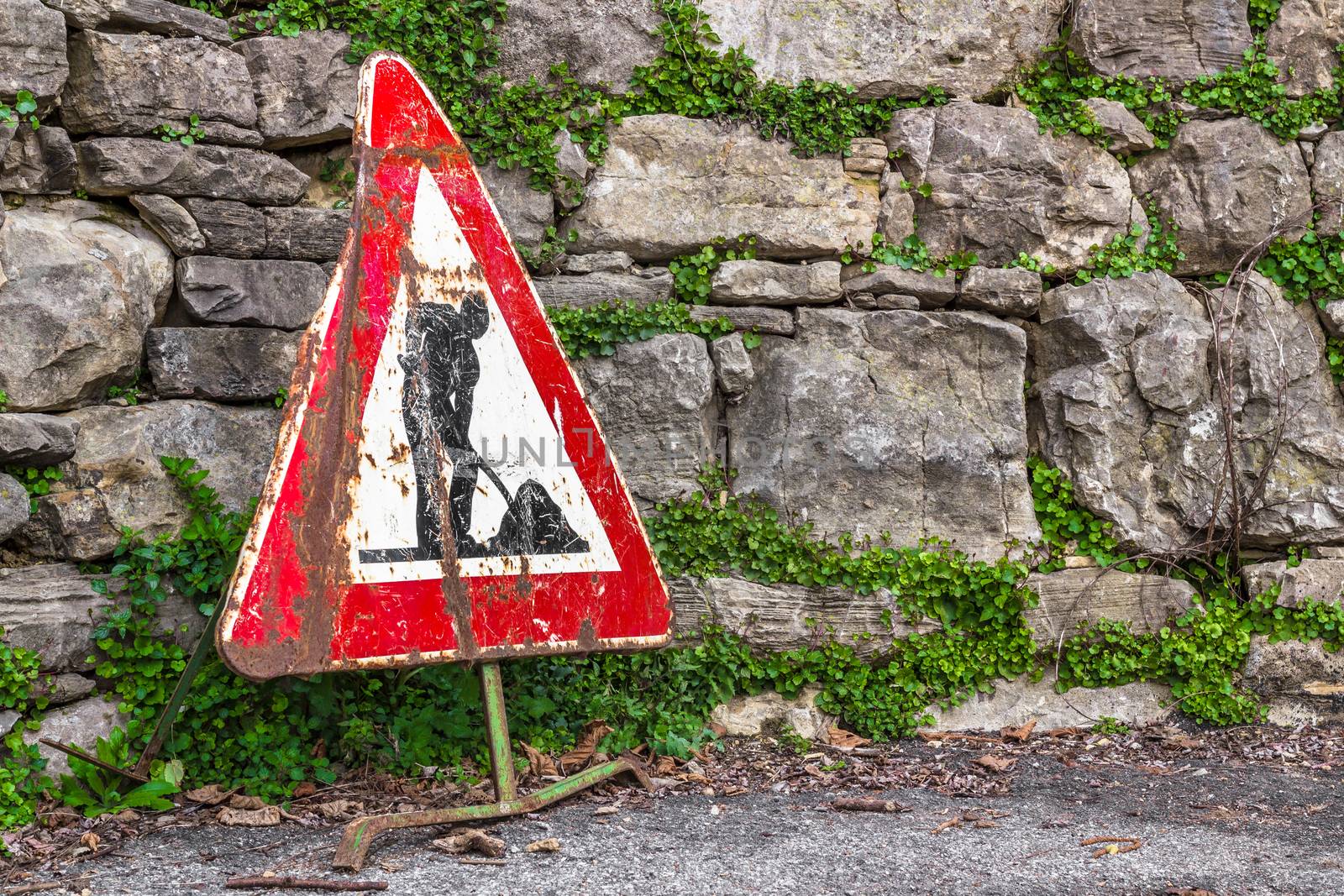 Old work in progress road sign with brick wall on background.