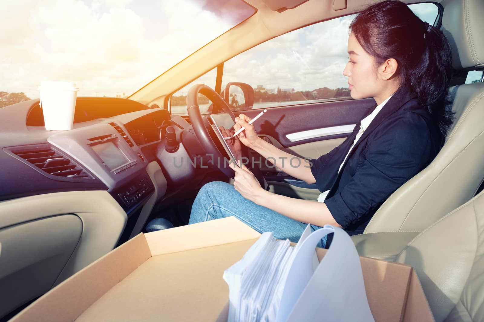 Young working woman using digital tablet in the car