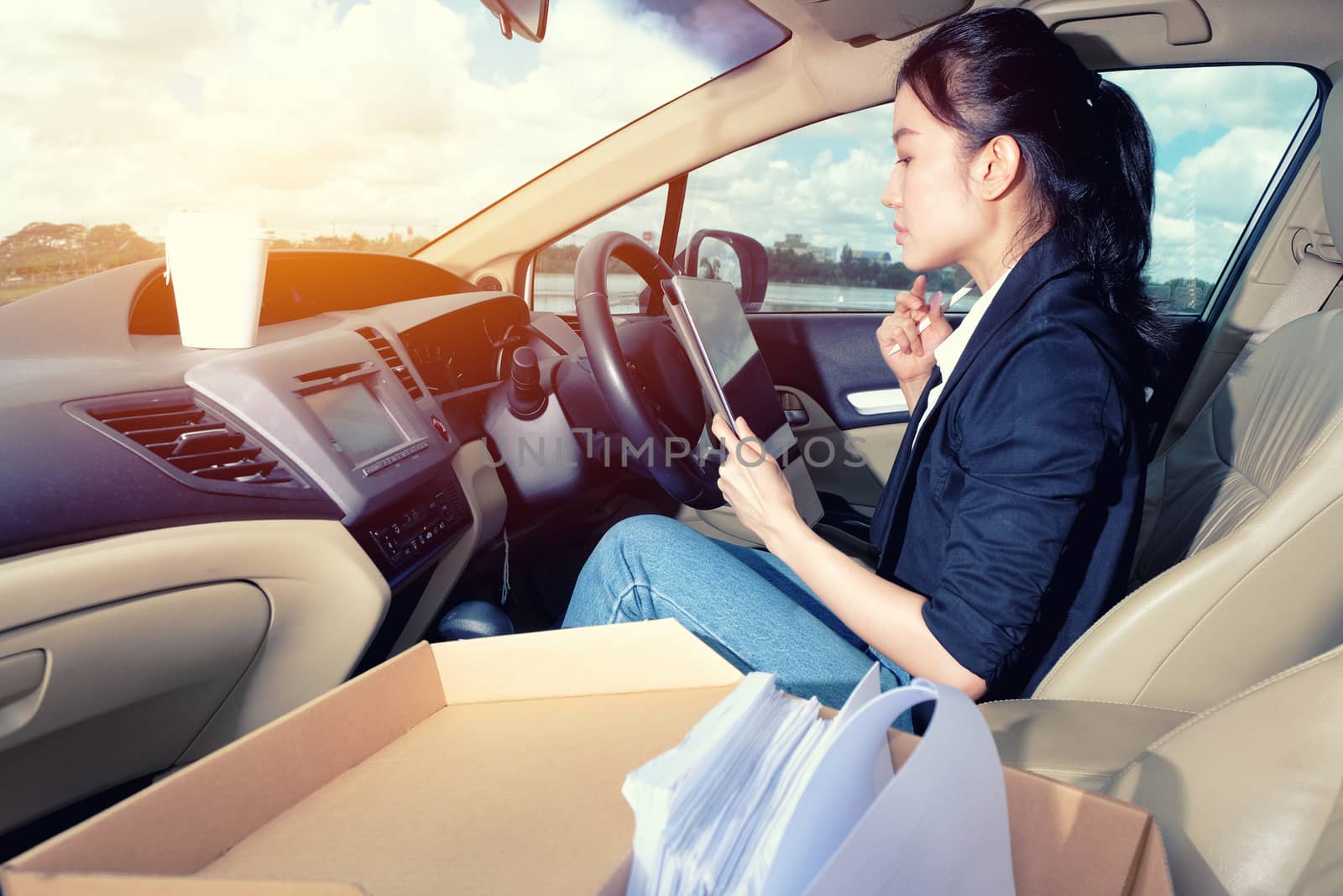 Young working woman using digital tablet in the car