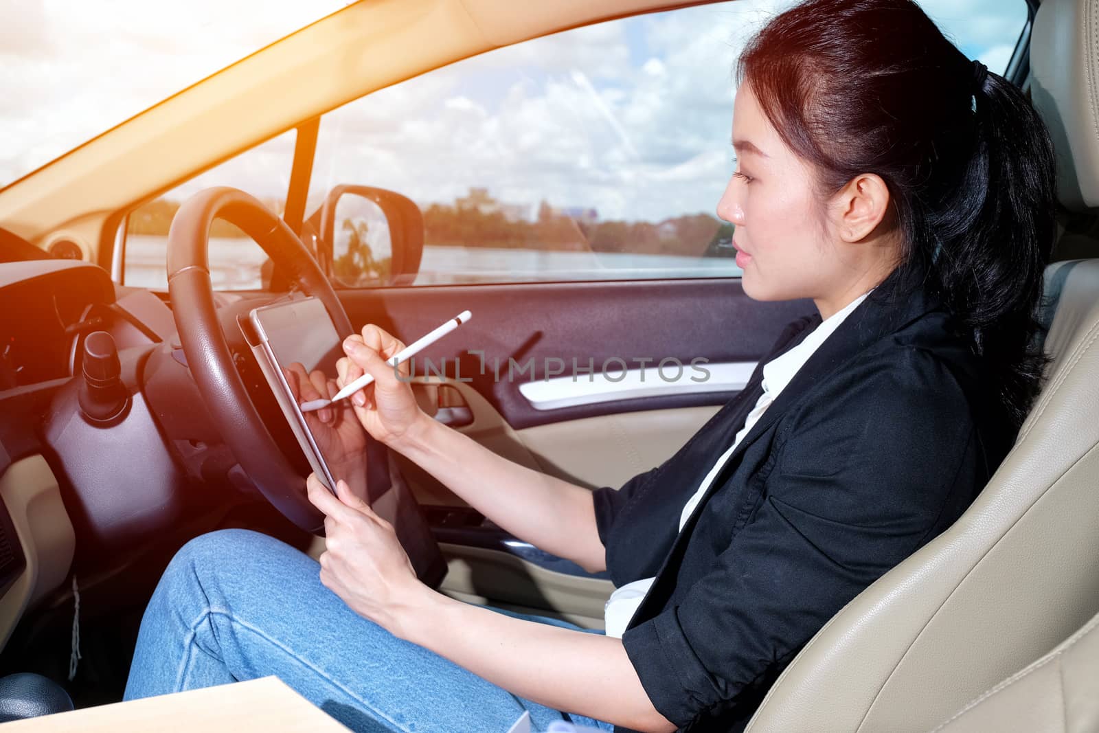 Young working woman using digital tablet in the car by Surasak