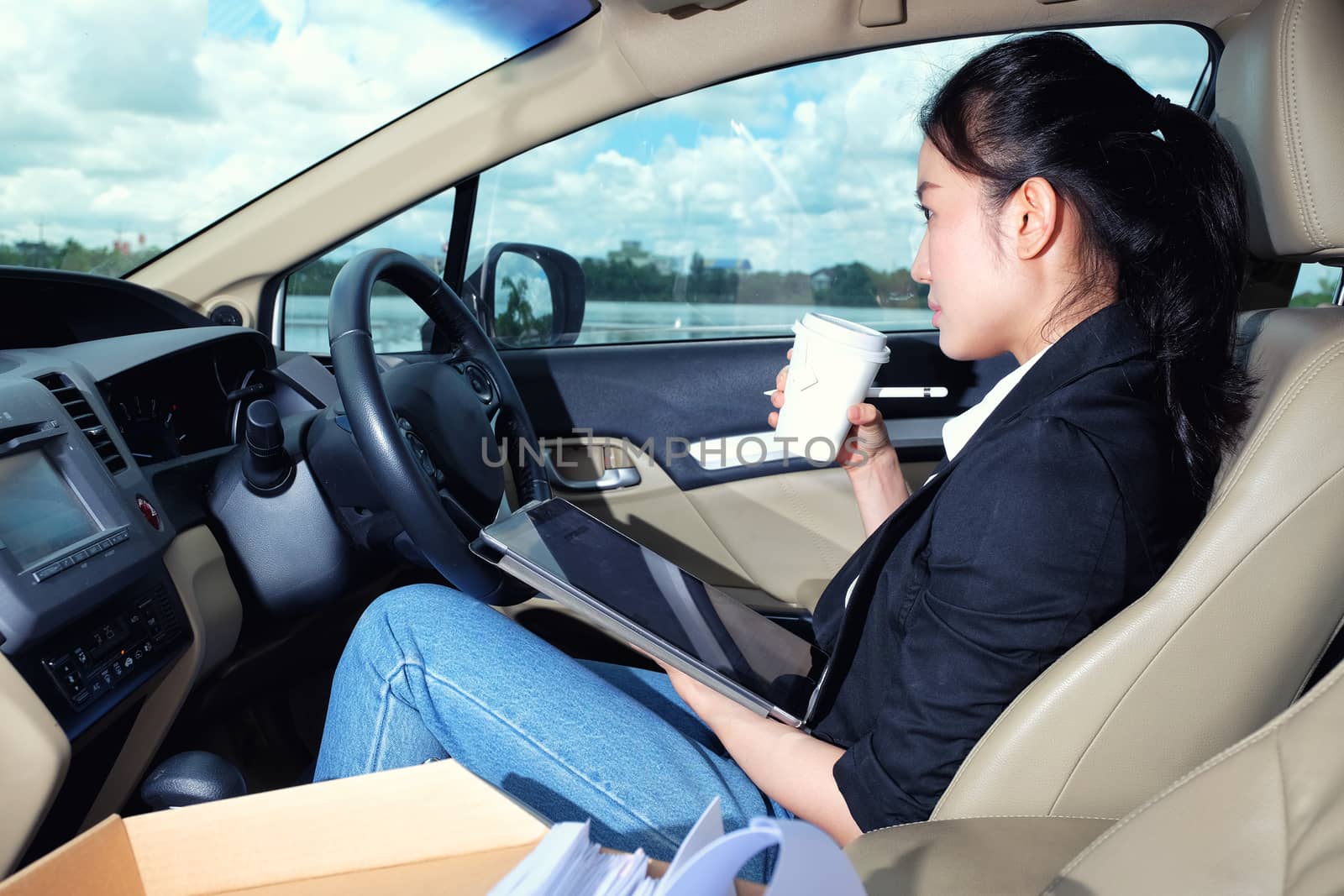 Young working woman using digital tablet in the car