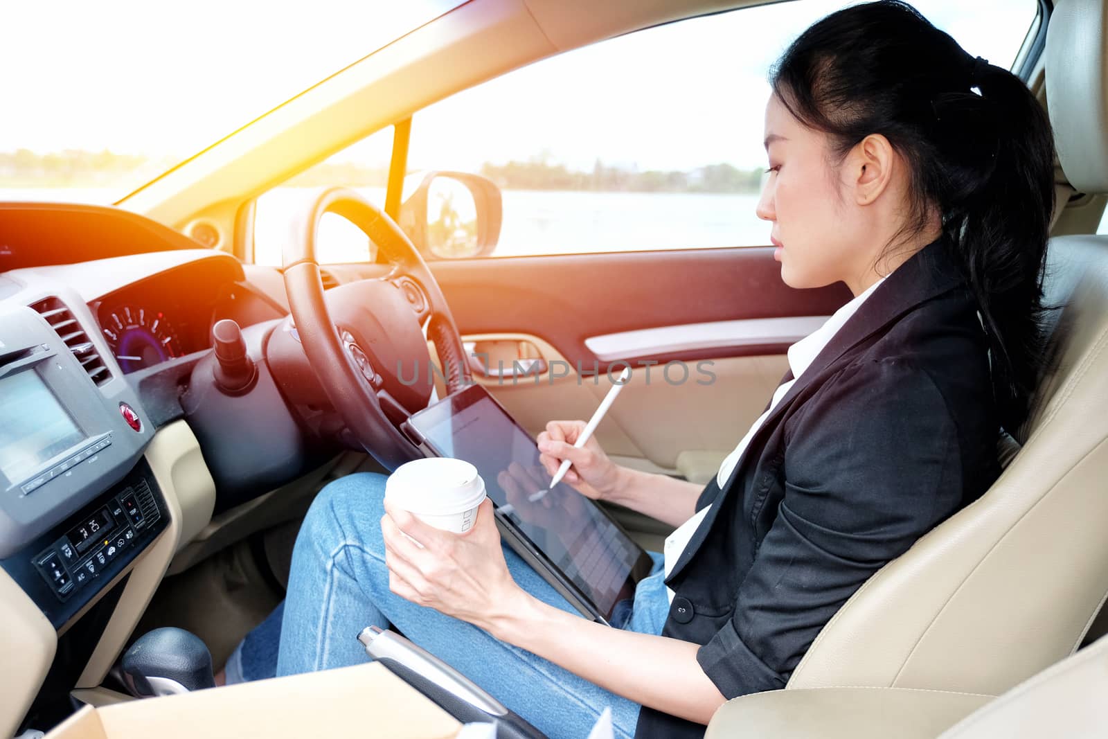 Young working woman using digital tablet in the car

 by Surasak