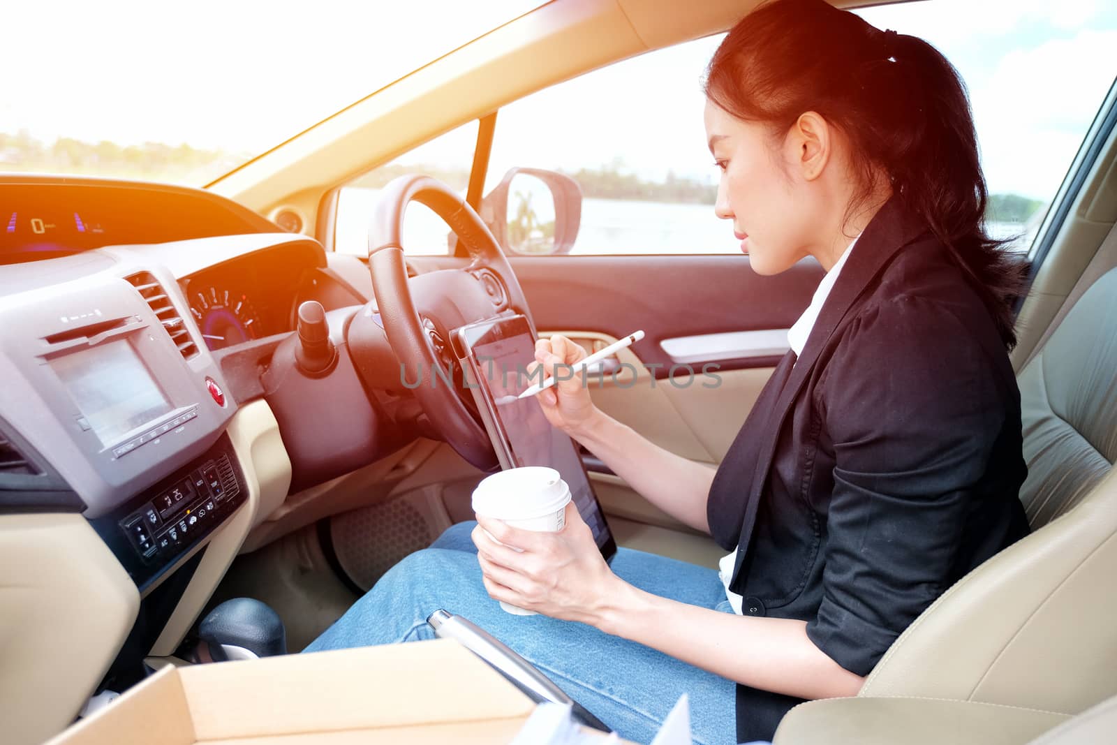 Young working woman using digital tablet in the car

