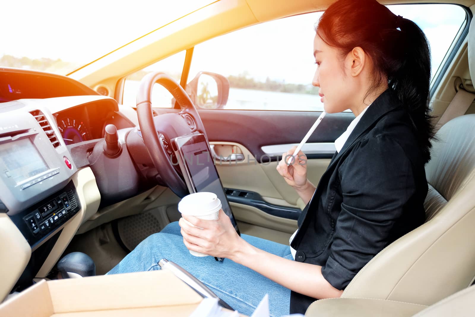 Young working woman using digital tablet in the car