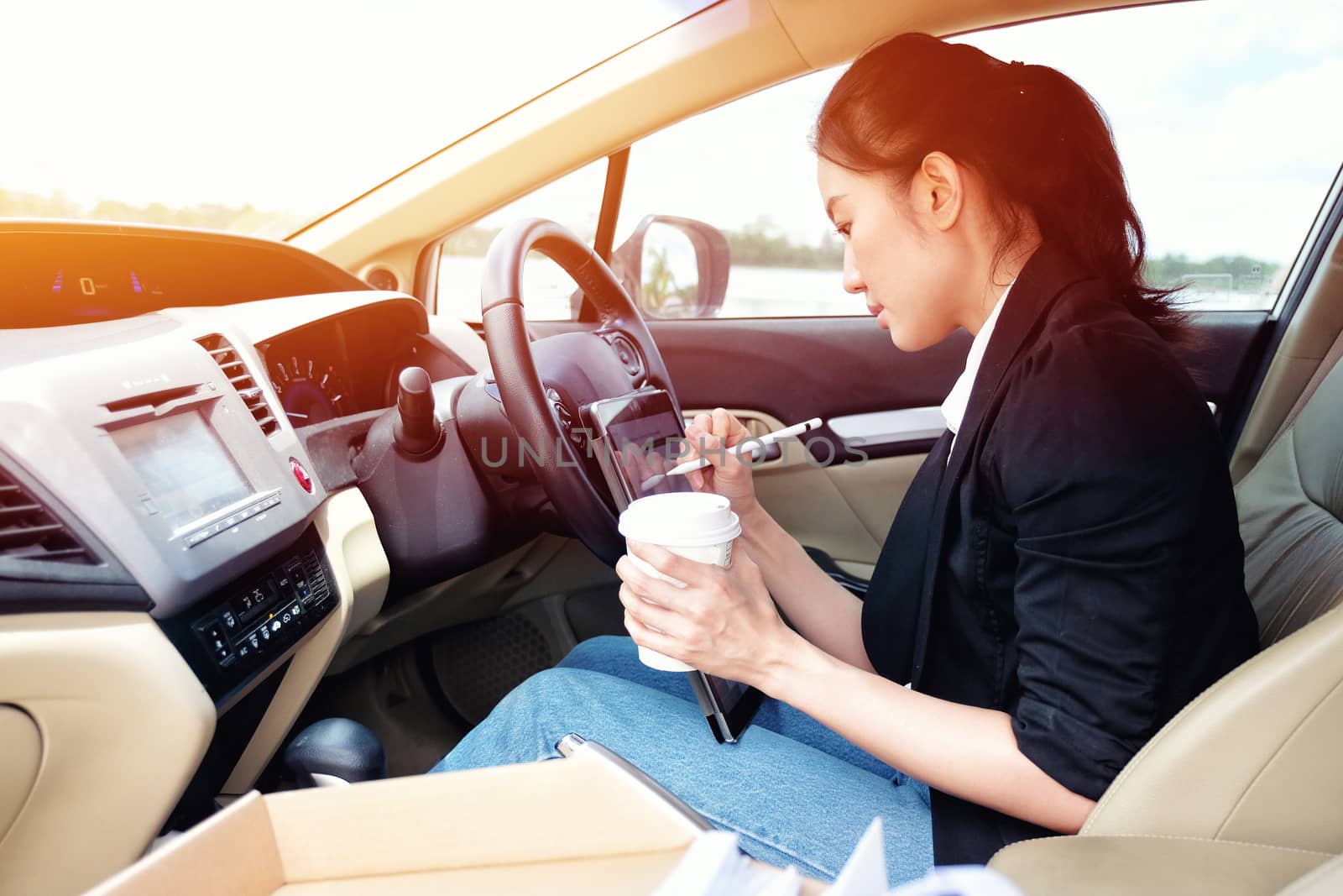 Young working woman using digital tablet in the car