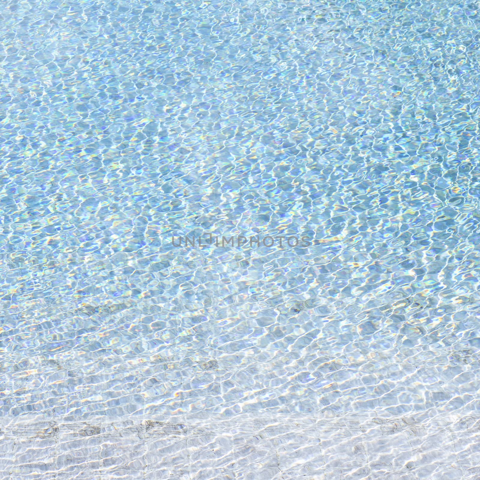 Blue swimming pool reflecting the sun rippled
