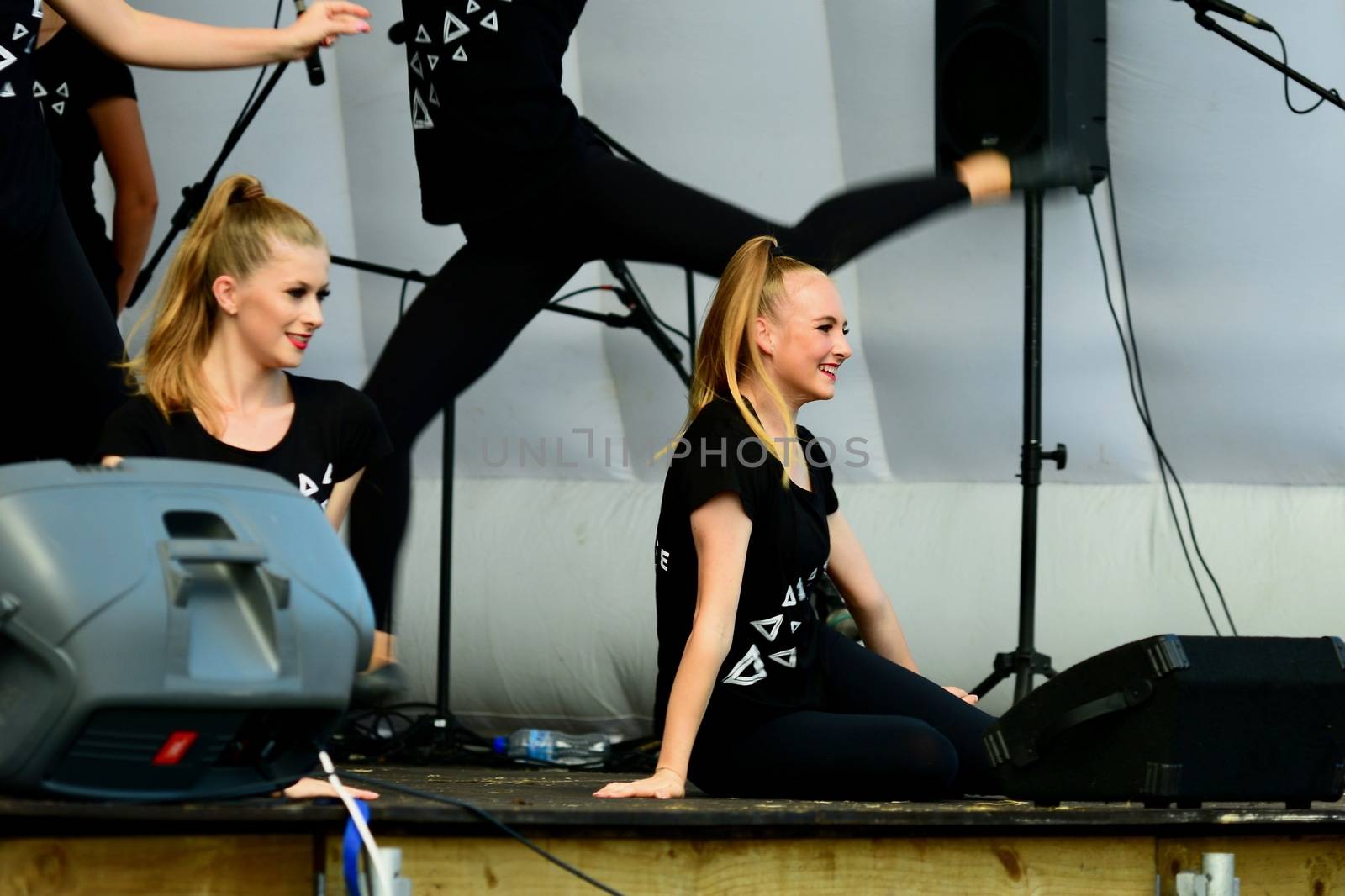 Beautiful unidentified girls dancing at an outdoor stage in a public park.