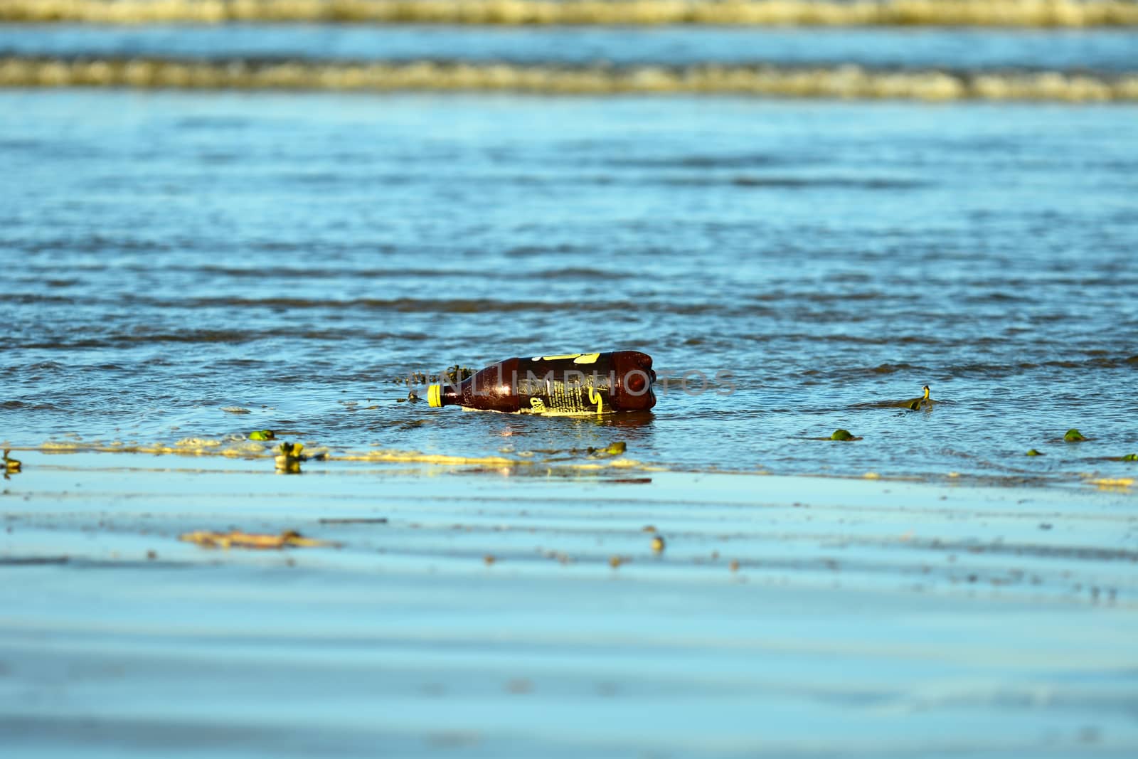Auckland, New Zealand - Jan 2020. Sea pollution, with a plastic bottle washed ashore on a beach. by Marshalkina