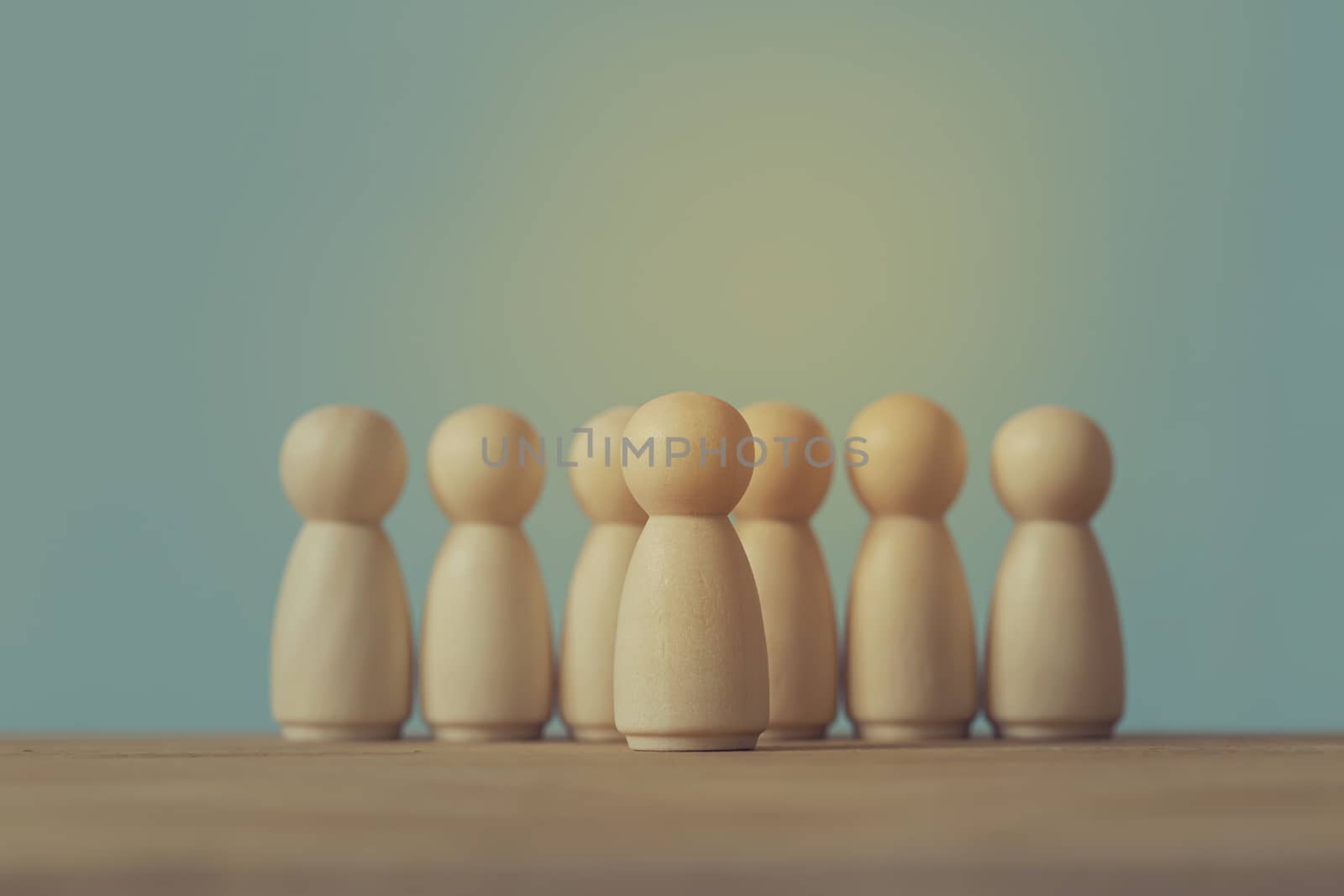 Successful business team leader concept: Wooden figures of man and people standing out from the crowd. depicts ability of individual to influence and lead followers or other members of organization.