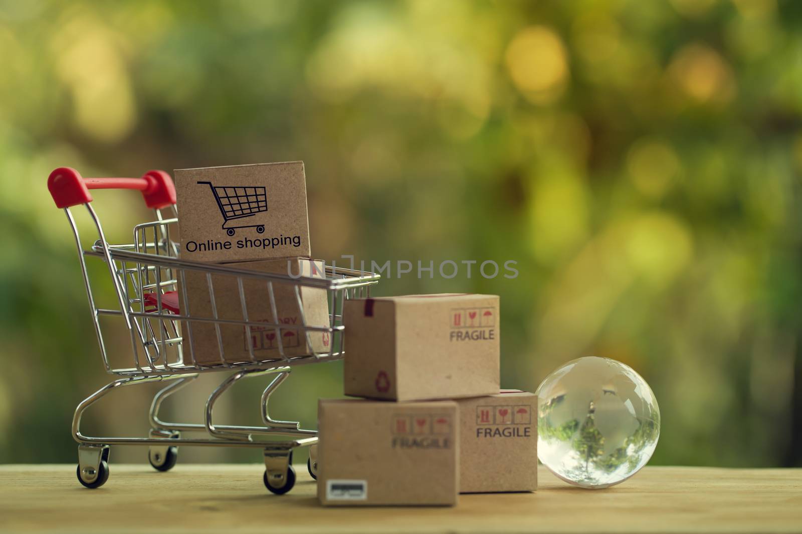 Shopping Online and e-commerce concept: Paper boxes in shopping cart and crystal globe. Trading management system so that customers can buy products and services from that operator at all times