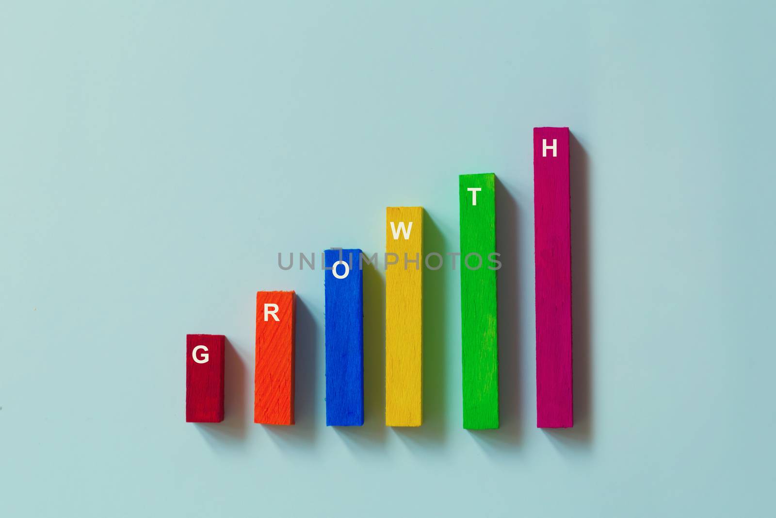 Progress or success concept. Arrange color wood bar graph with word GROWTH on blue background. Risk management business financial and managing investment for long term growth.