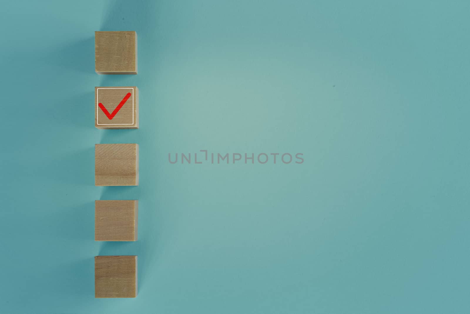 Wooden blocks with checking mark on checklist with blue background