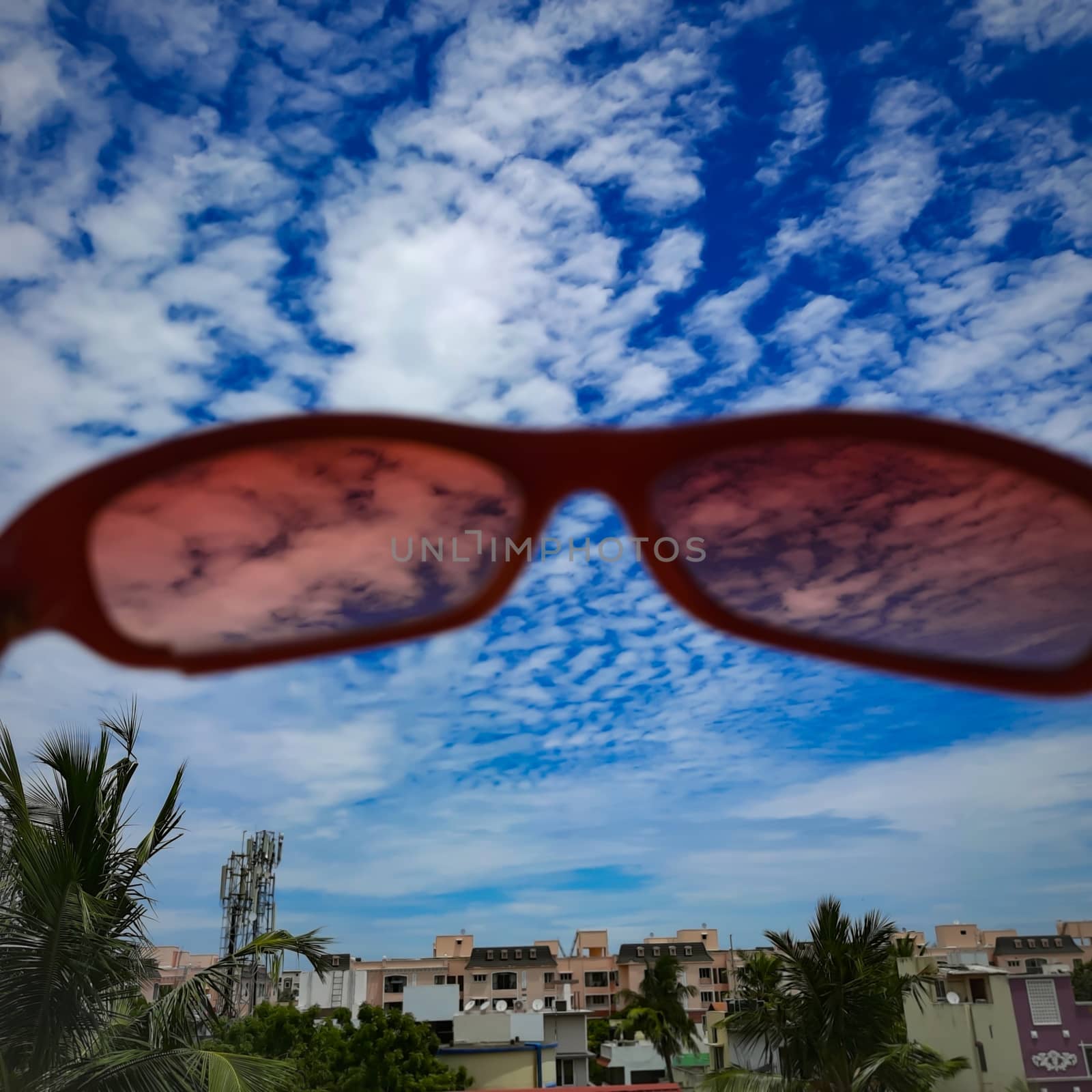 Chennai, India - July 3 2020: Red color glass placed in wall to see beautiful view of the sky from the glass lens and foreground view of buildings