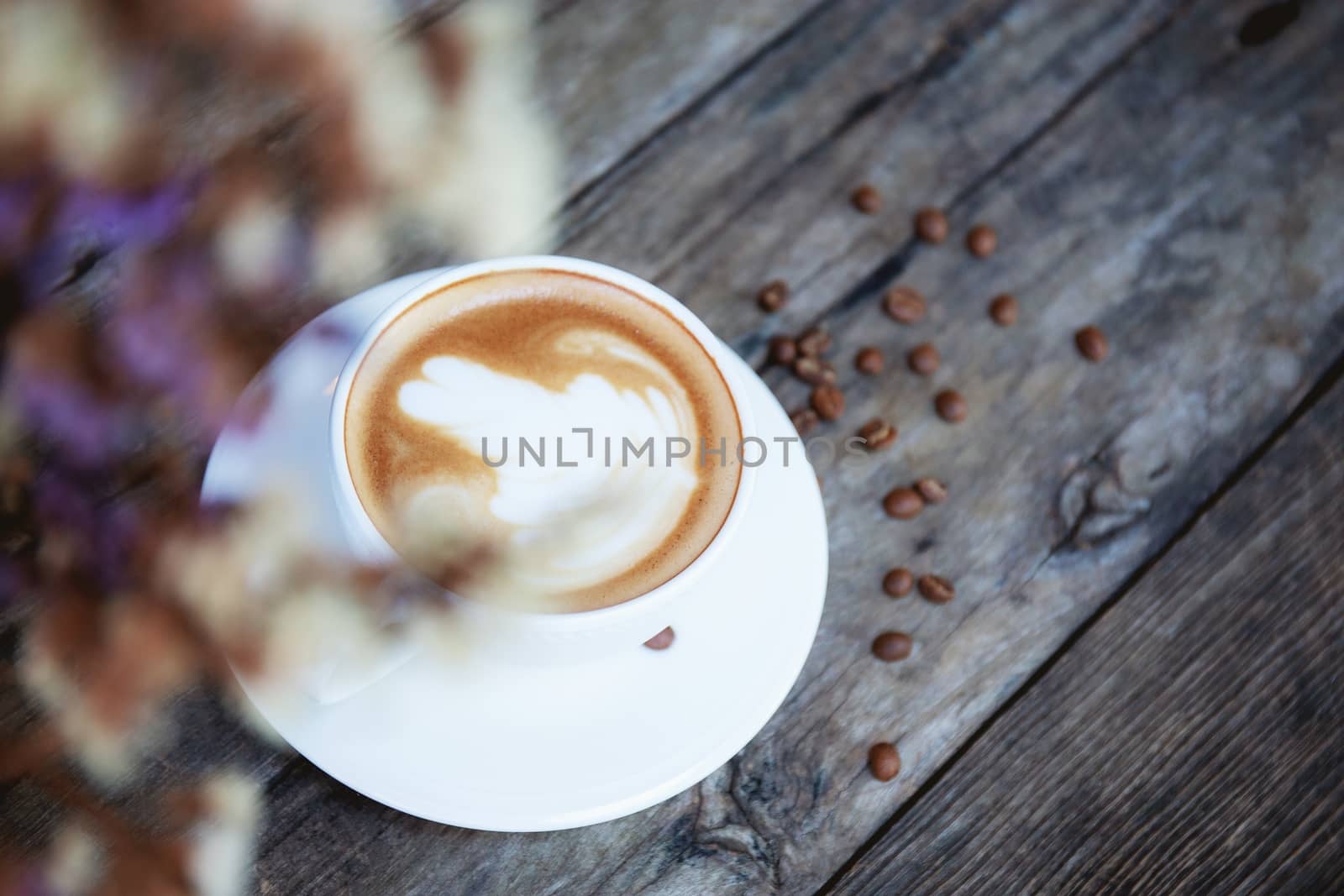 Coffee cup and flower on wood with background.