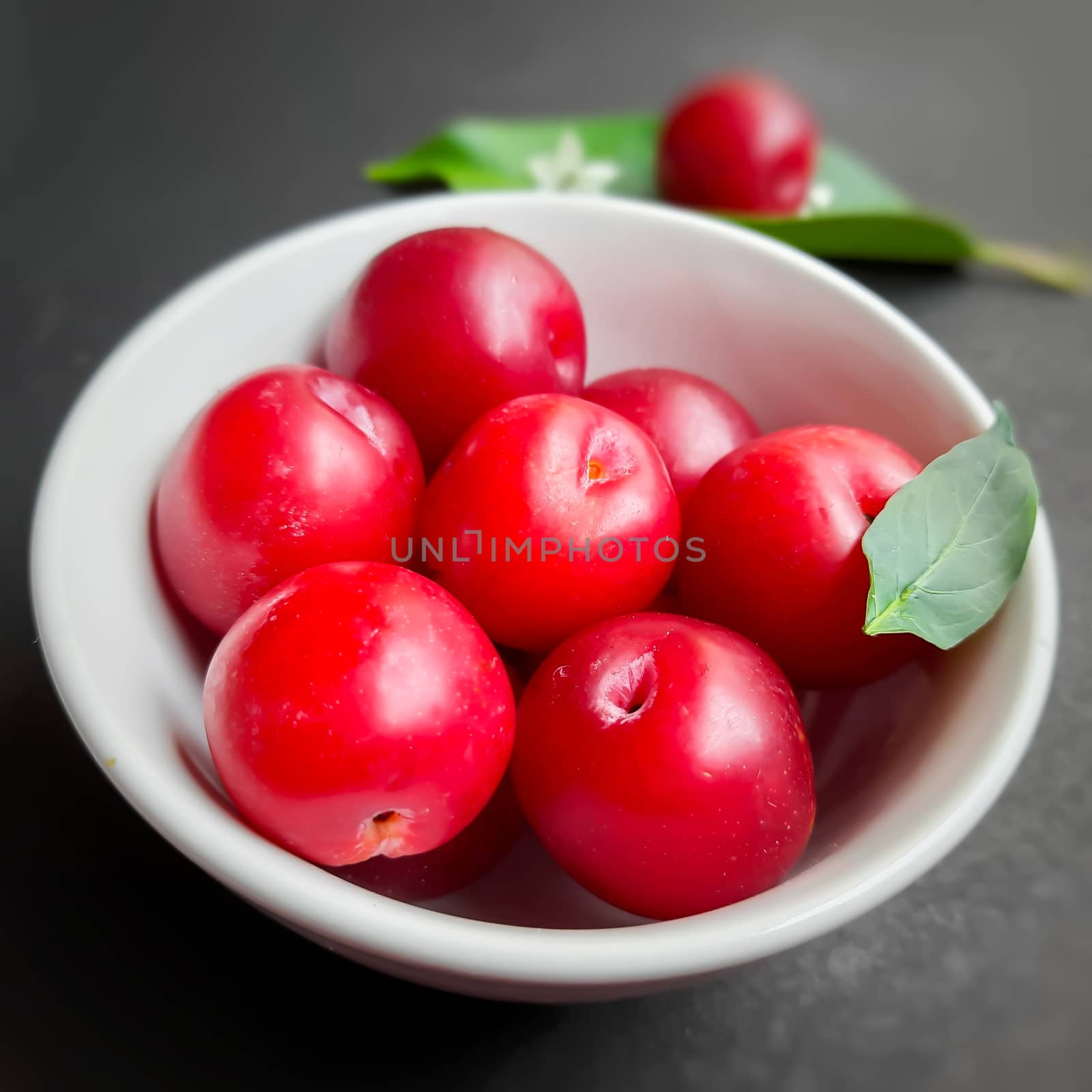 Colorful Red plums kept in bowl placed in black backgrounds and plated with leaf with plums and reduce the risk of cancer heart disease and diabetes