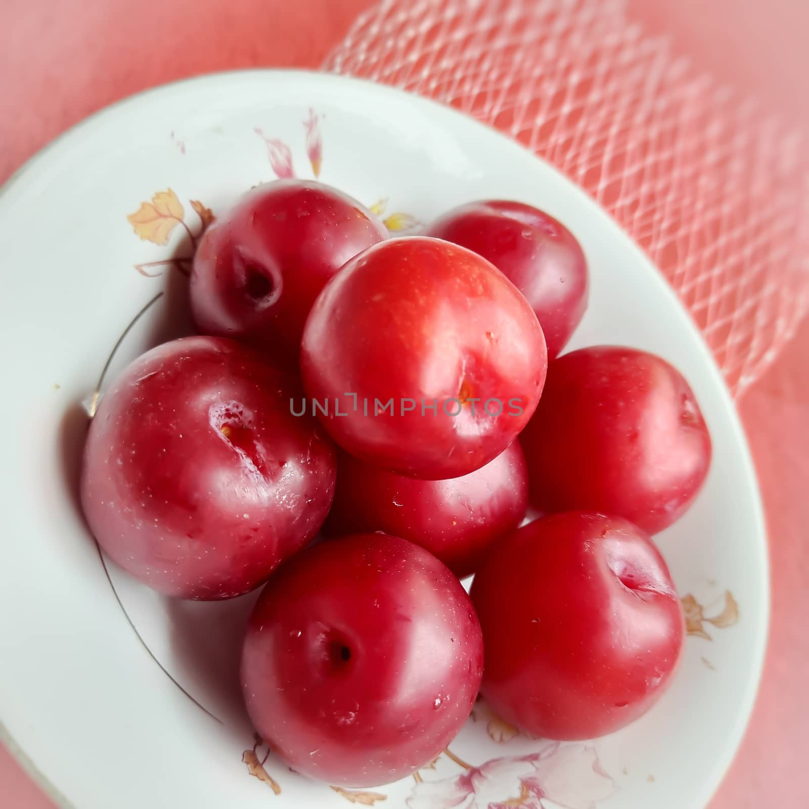 Colorful Red plums kept in bowl placed in red backgrounds and reduce the risk of cancer heart disease and diabetes by AnithaVikram