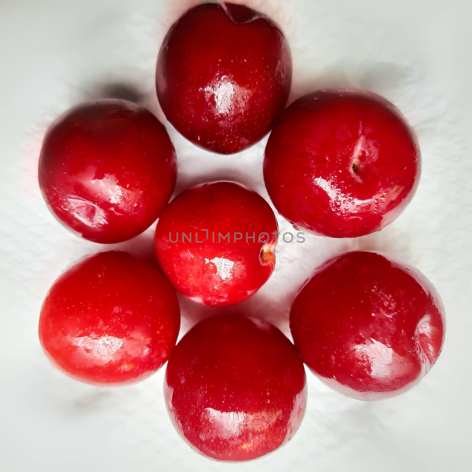 Colorful Red plums placed in white background and reduce the risk of cancer heart disease and diabetes by AnithaVikram