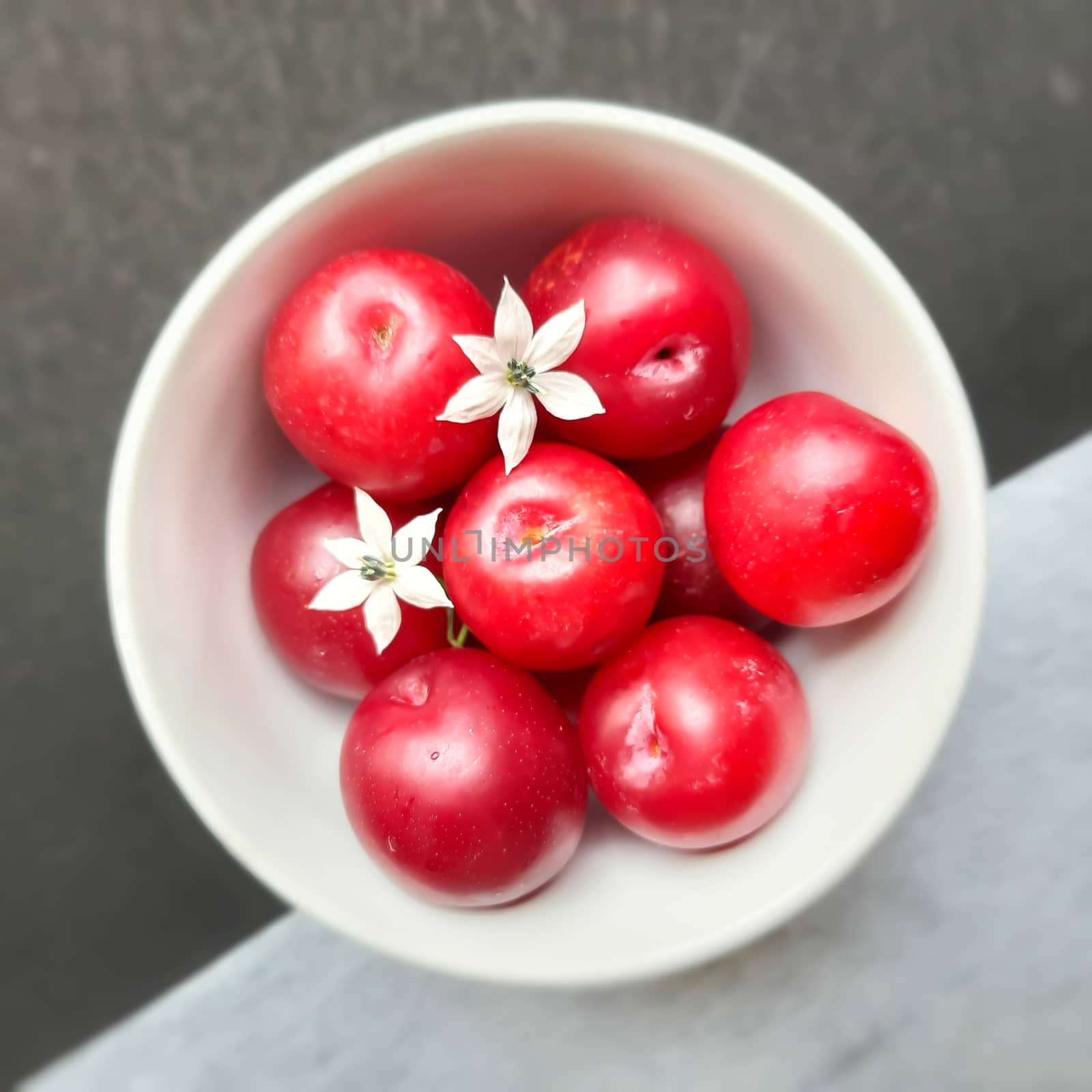 Colorful Red plums kept in bowl placed in white and black background and reduce the risk of cancer heart disease and diabetes