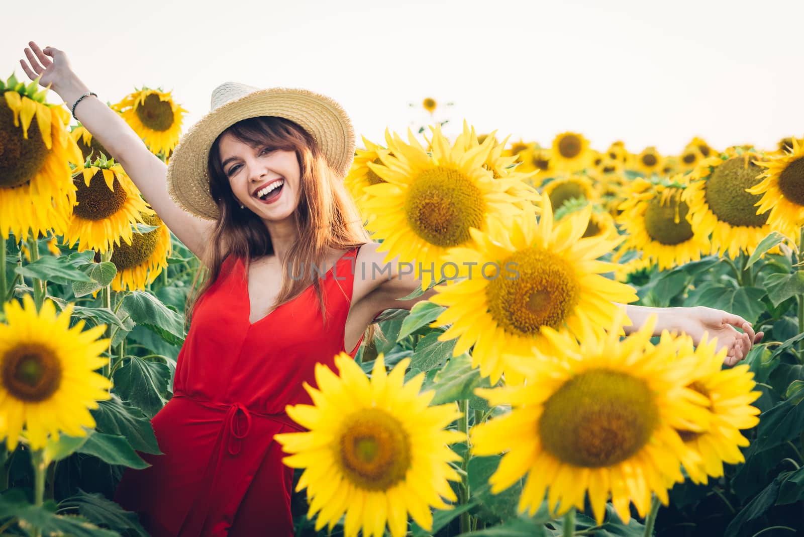 happy woman with red dress and hat in field of sunflowers