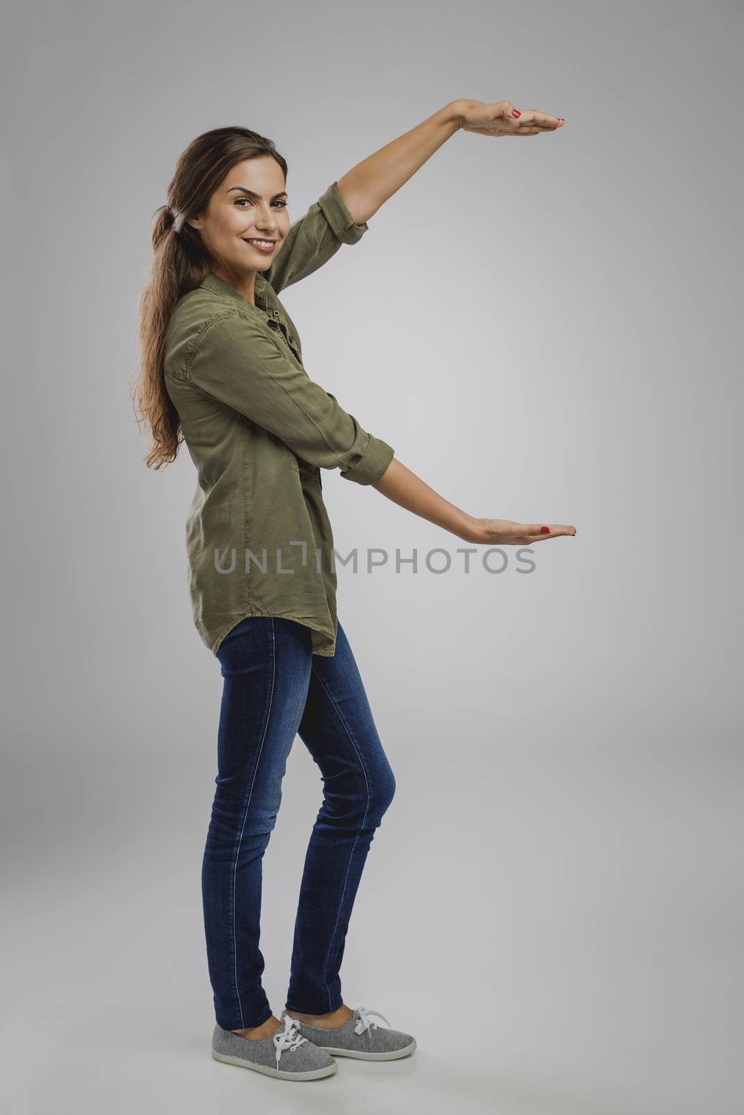 Beautiful woman over a gray background showing something her arms