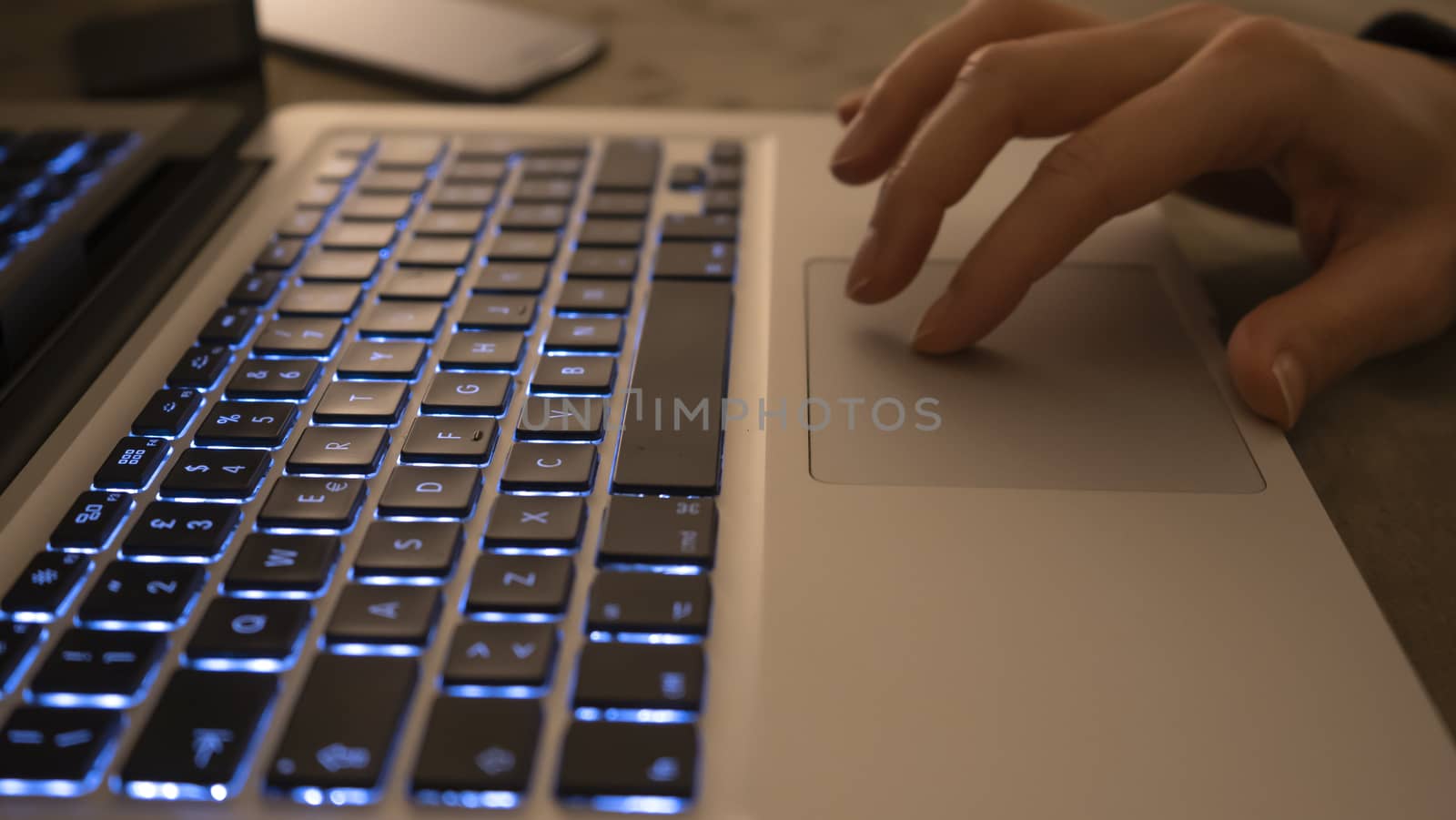 Couple relationships and dating in modern times concept: closeup of woman's hands typing on laptop keyboard in low light ambient by robbyfontanesi