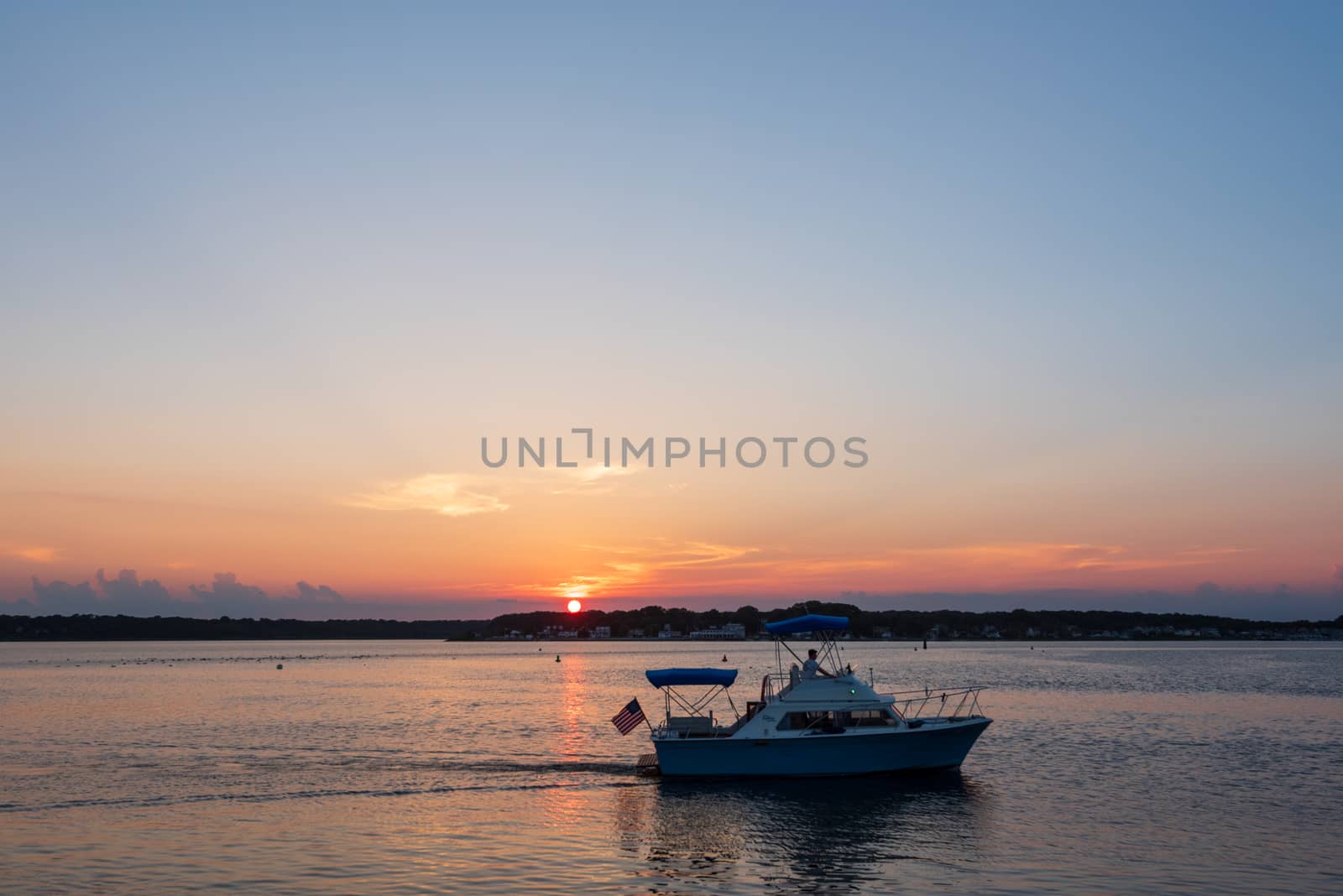 Belmar, NJ, USA -- July 19, 2017. A small boat sails in Shark River at sunset on a summer day in Belmar, NJ.