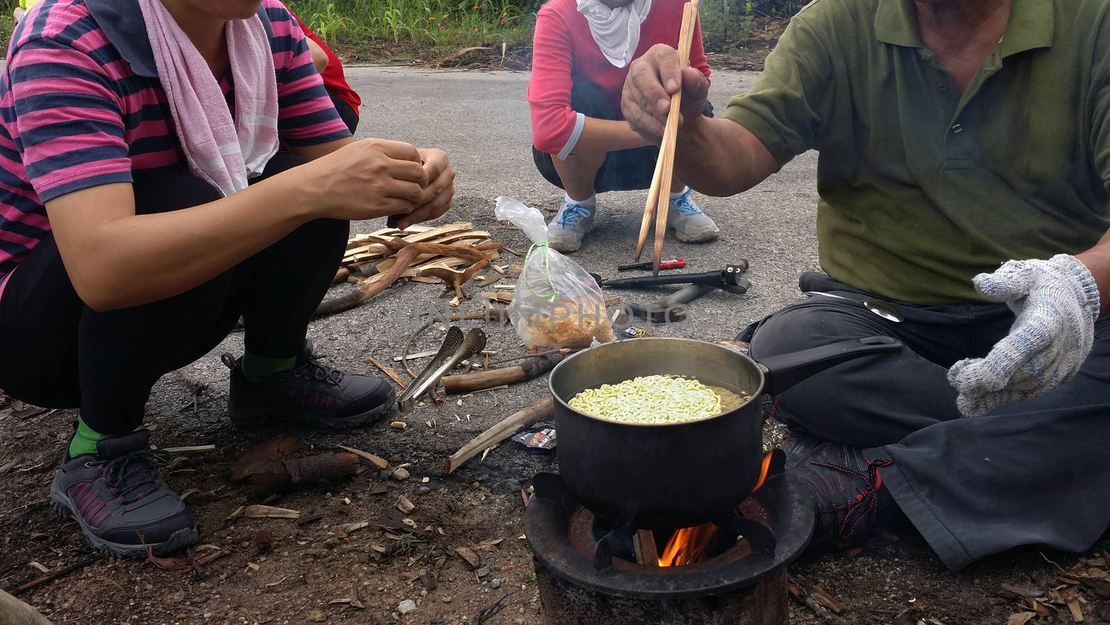 Cooking instant nodles at outdoors in black pot at picnic on fire.