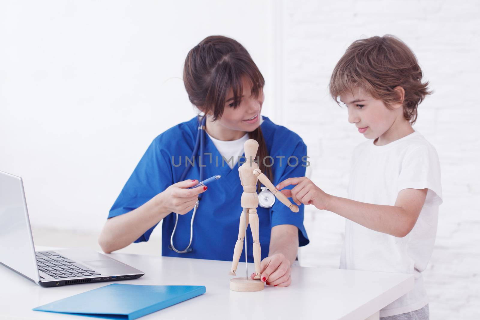 Doctor showing anatomical doll to her child patient in medical office