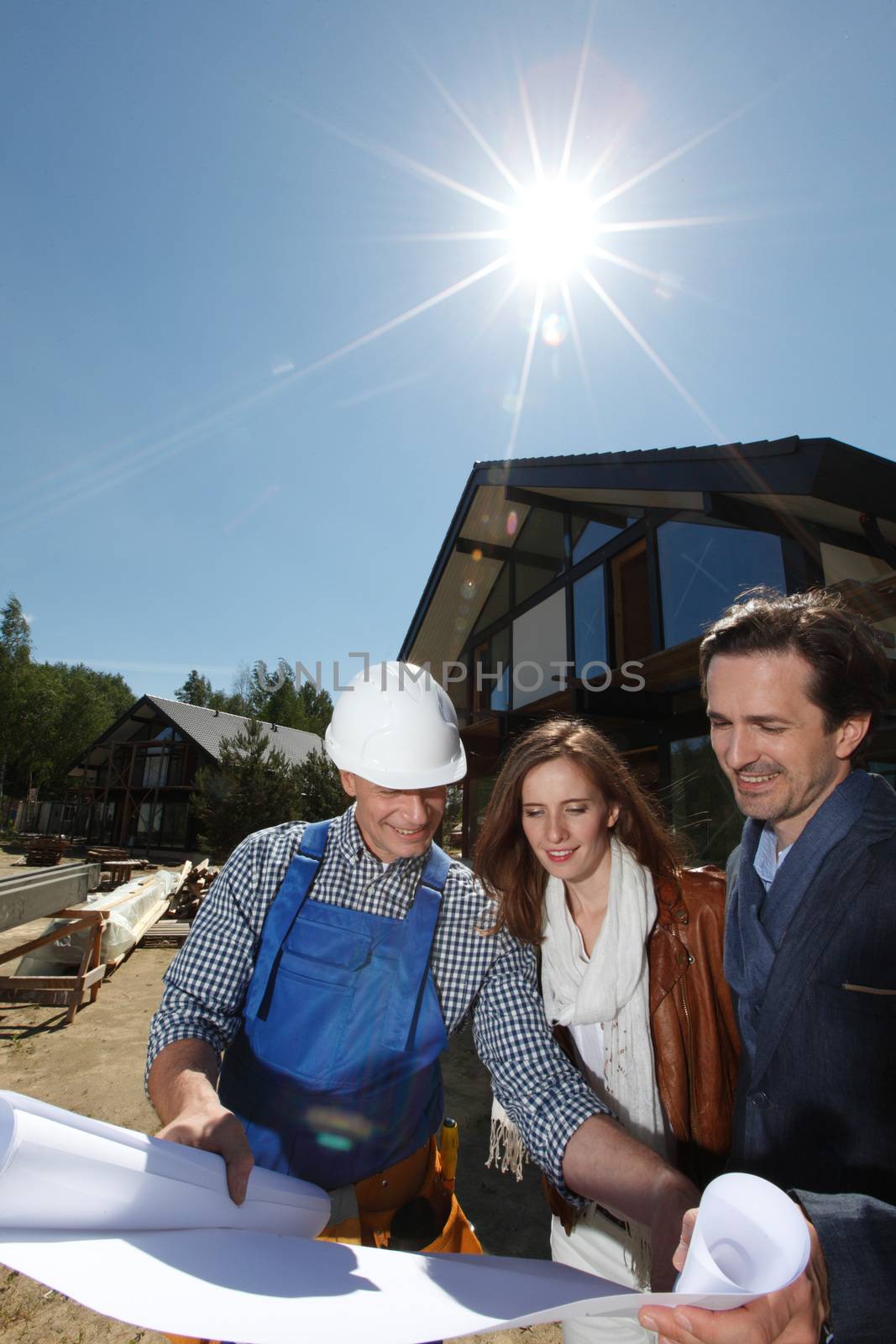 Foreman showing house design construction plan to a happy young couple new house real estate concept