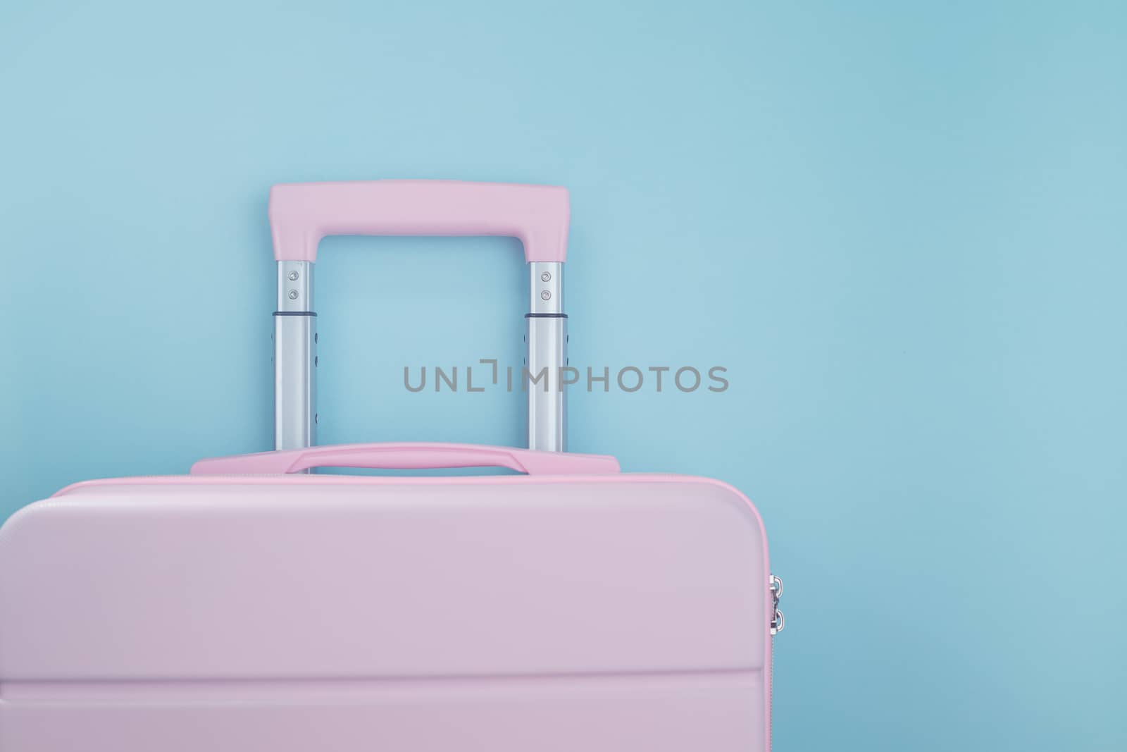 Pink luggage on blue pastel colored background for traveling concept