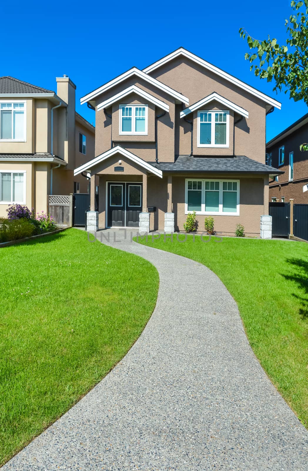 New house with concrete pathway over front yard lawn. Small family house in Vancouver, British Columbia