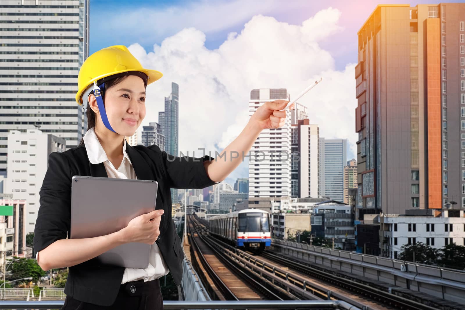 Young woman engineer holding digital tablet wtih smile in city skytrain background