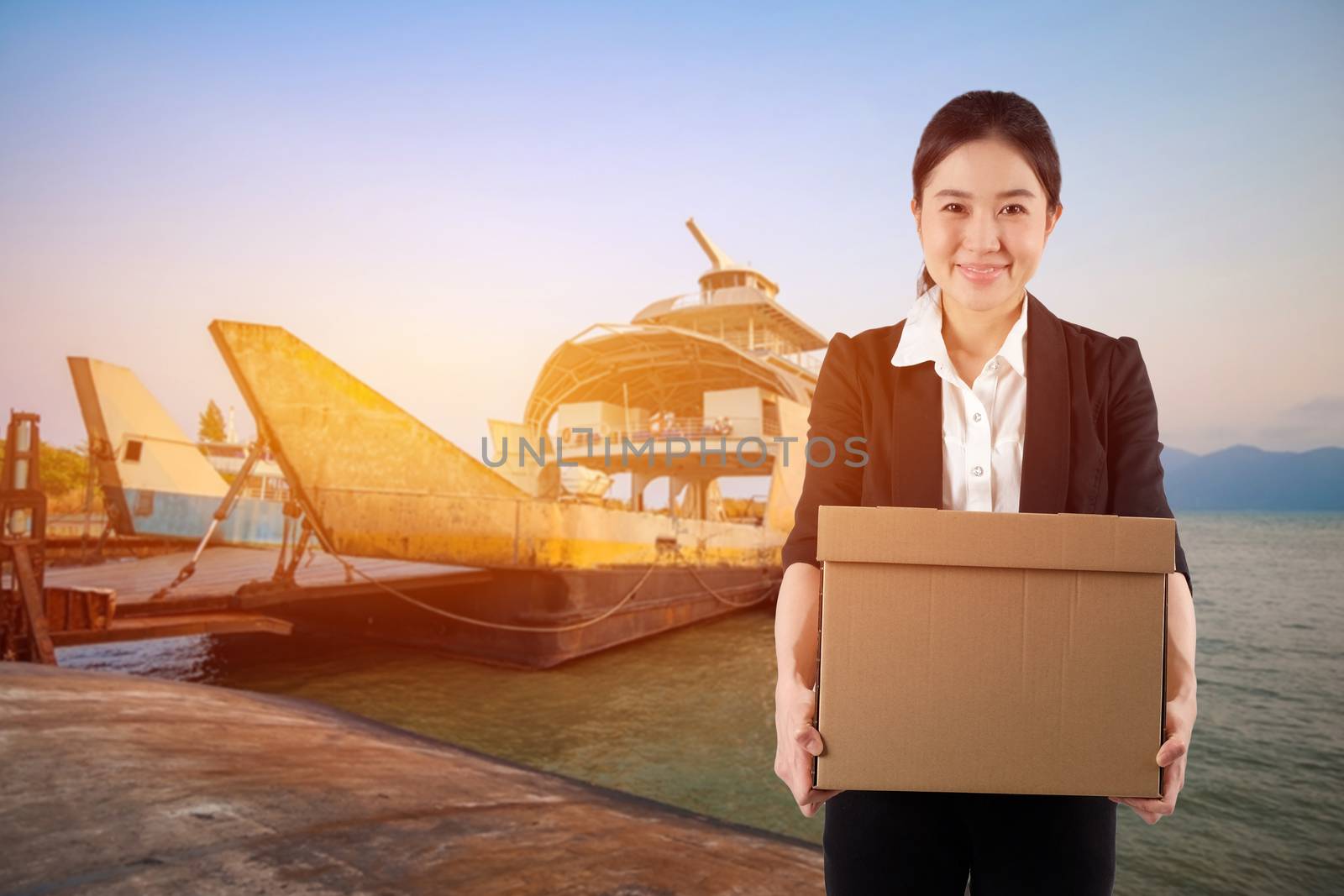 A young woman carrying a box wtih smiling on Cargo Ship background

