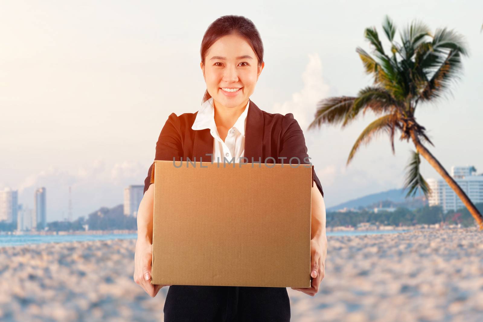 A young woman carrying a box on the beach background