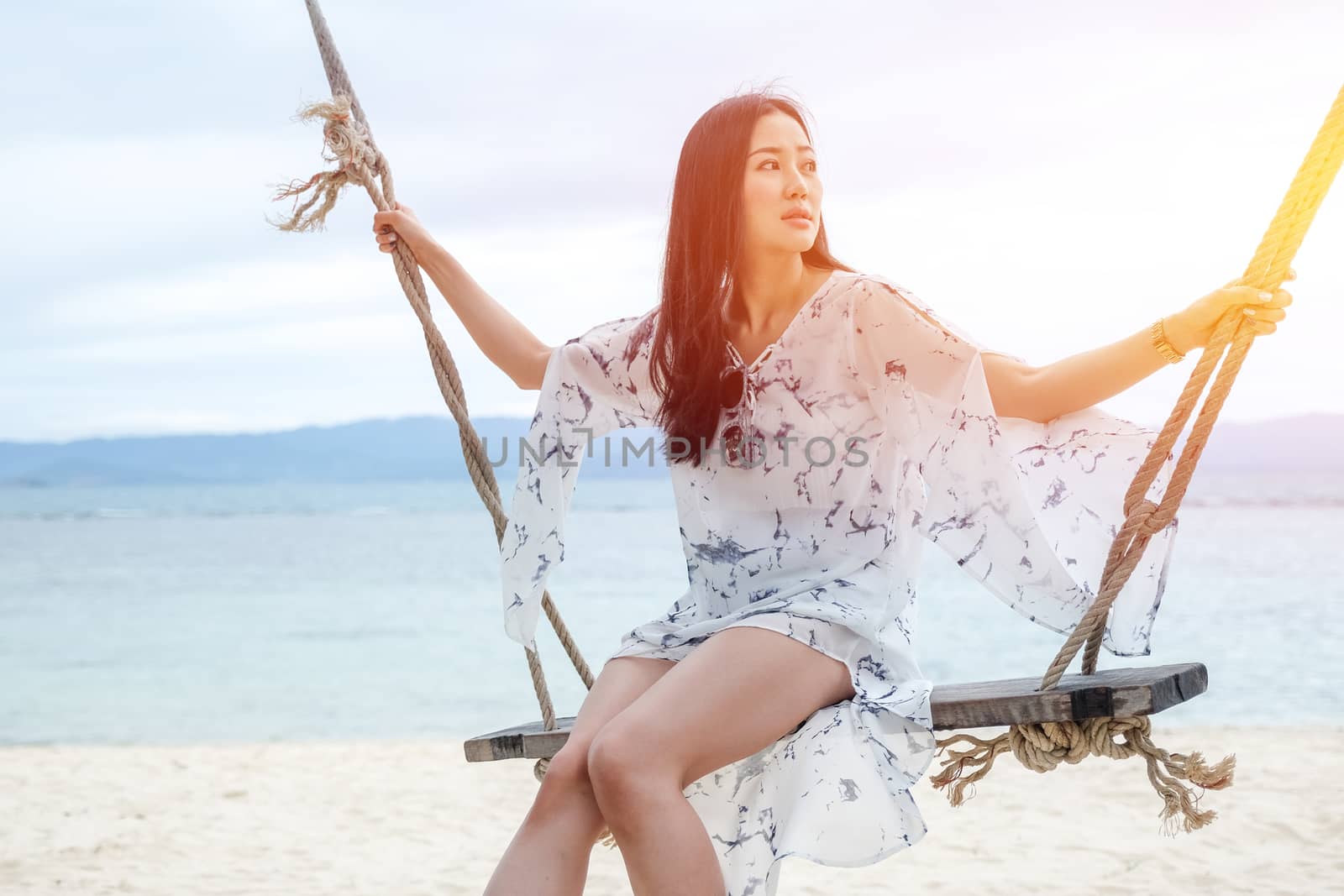 Beautiful woman sitting on a swing on the beach  in Koh Phangan, Thailand