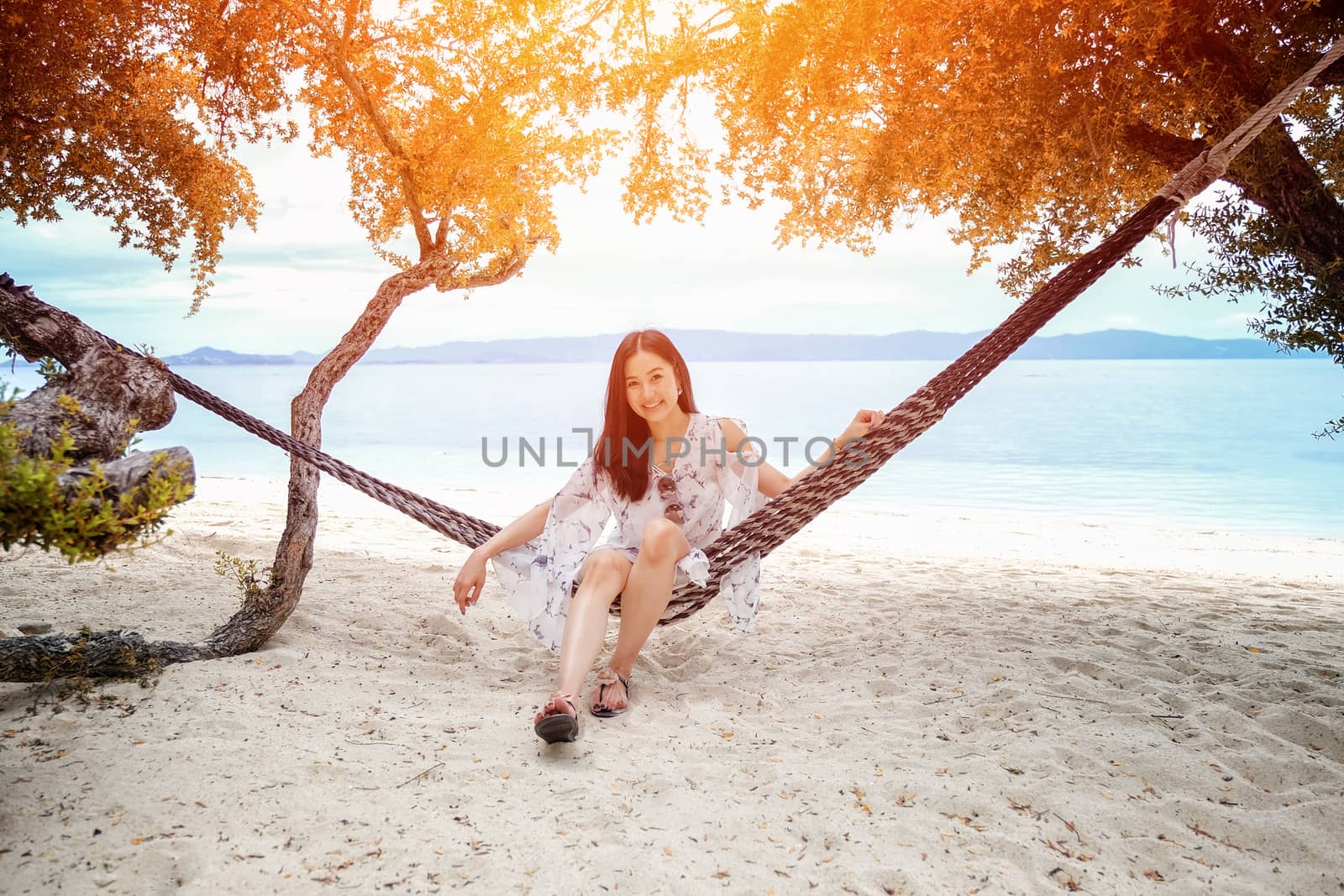 Beautiful woman sitting on a swing on the beach  in Koh Phangan, Thailand